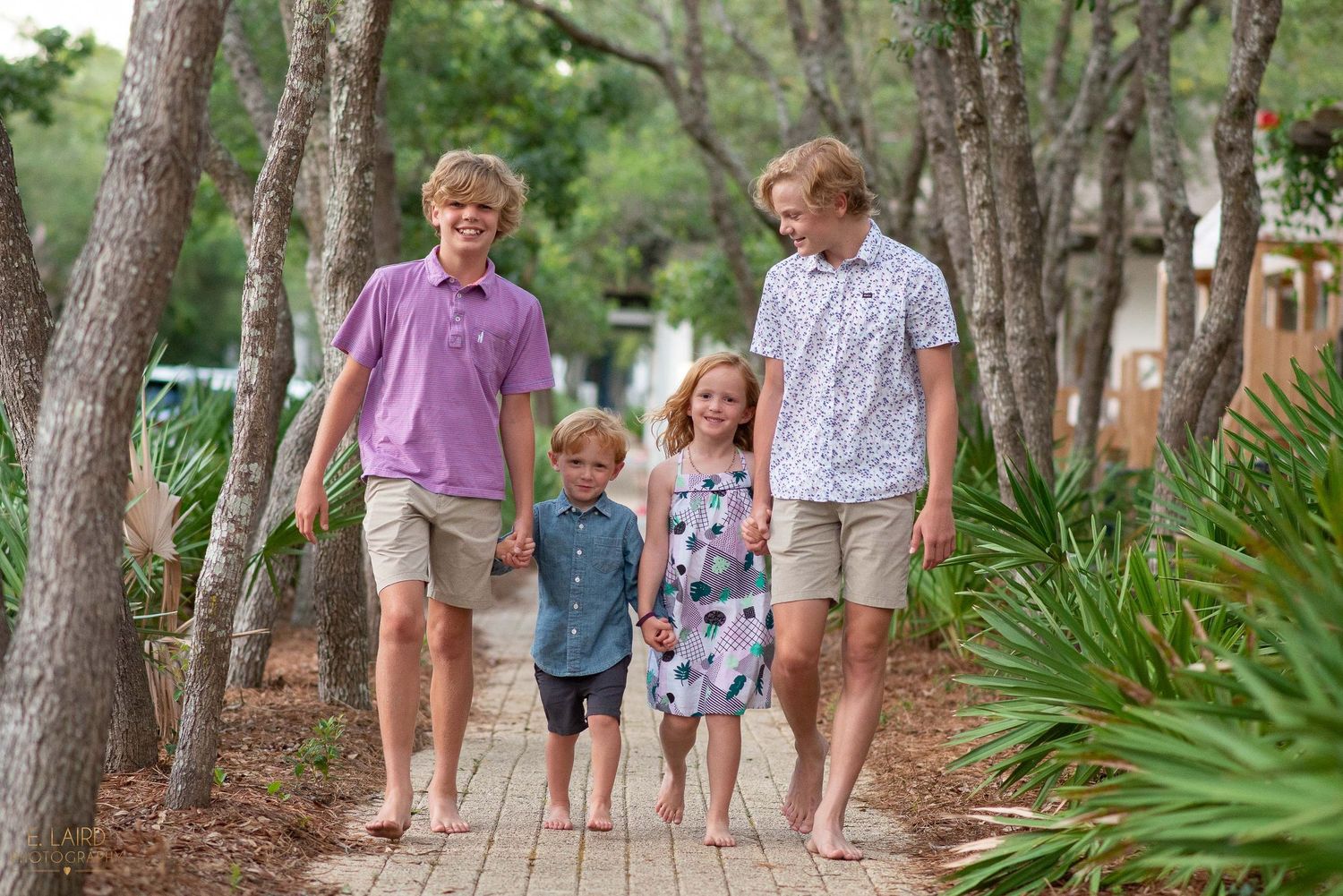 Family walking together on a wooden pathway through trees.