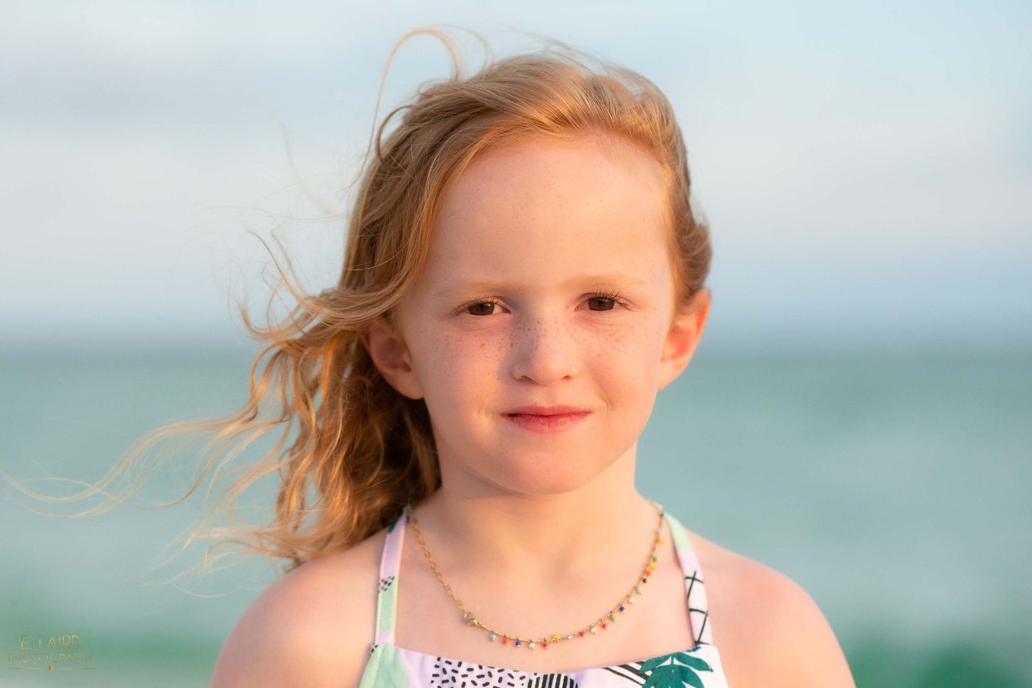Young child with windswept hair against ocean background.