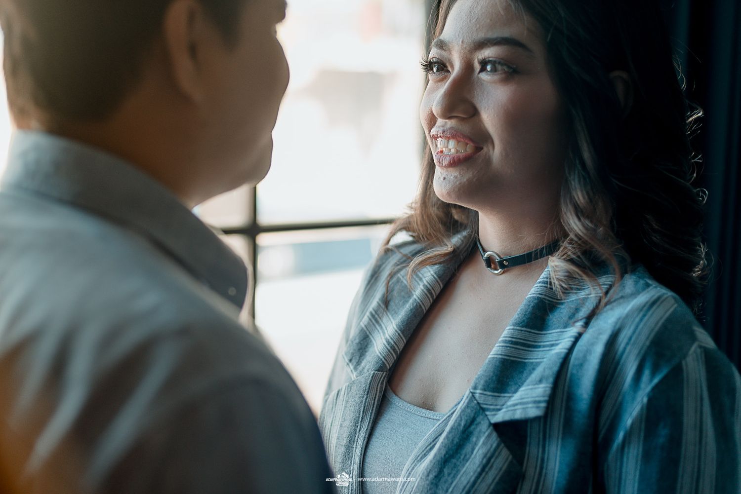 An intimate portrait capturing a sweet moment between a couple by a window.