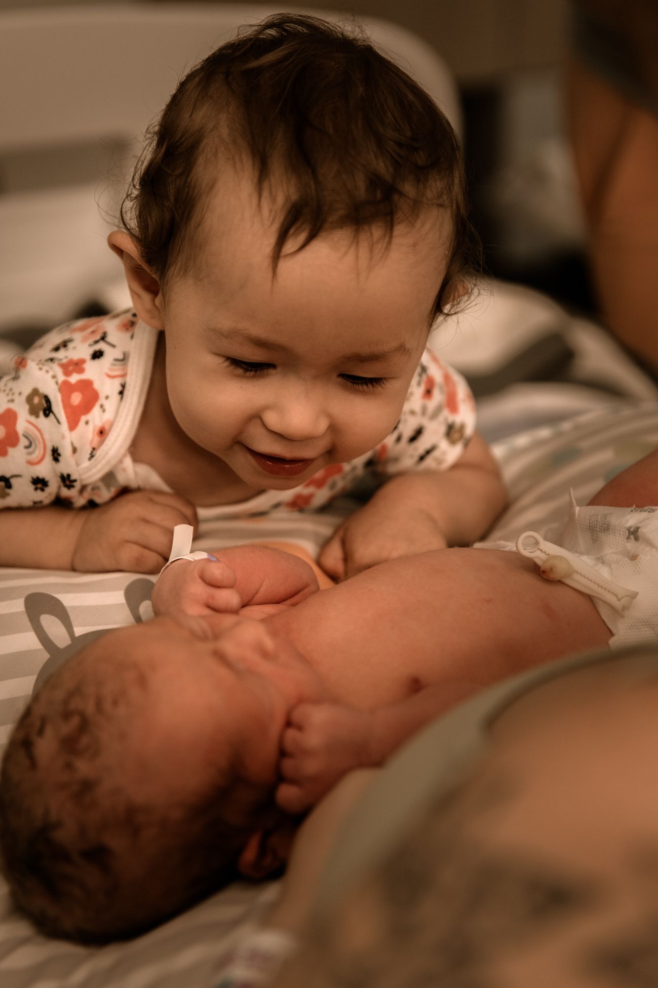 Two young children laying on bed sharing a sweet moment together, with one smiling warmly at the other.