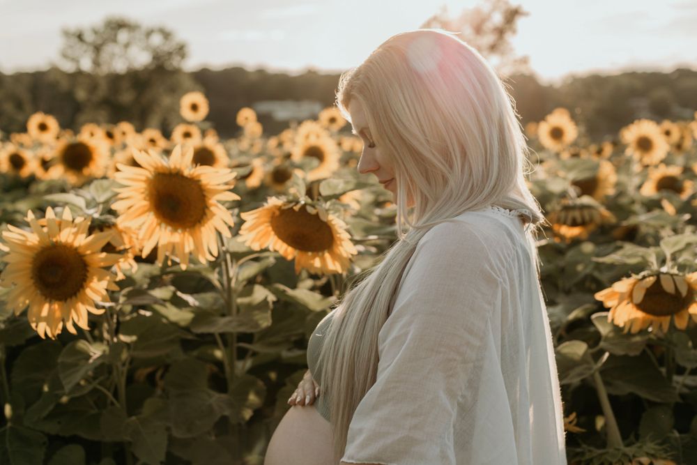 Person in white dress walking through vibrant sunflower field at golden hour.