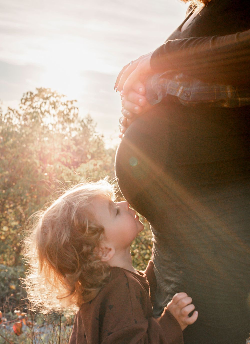 Ethereal sunlit portraits capture a moment of joy in a natural outdoor setting.