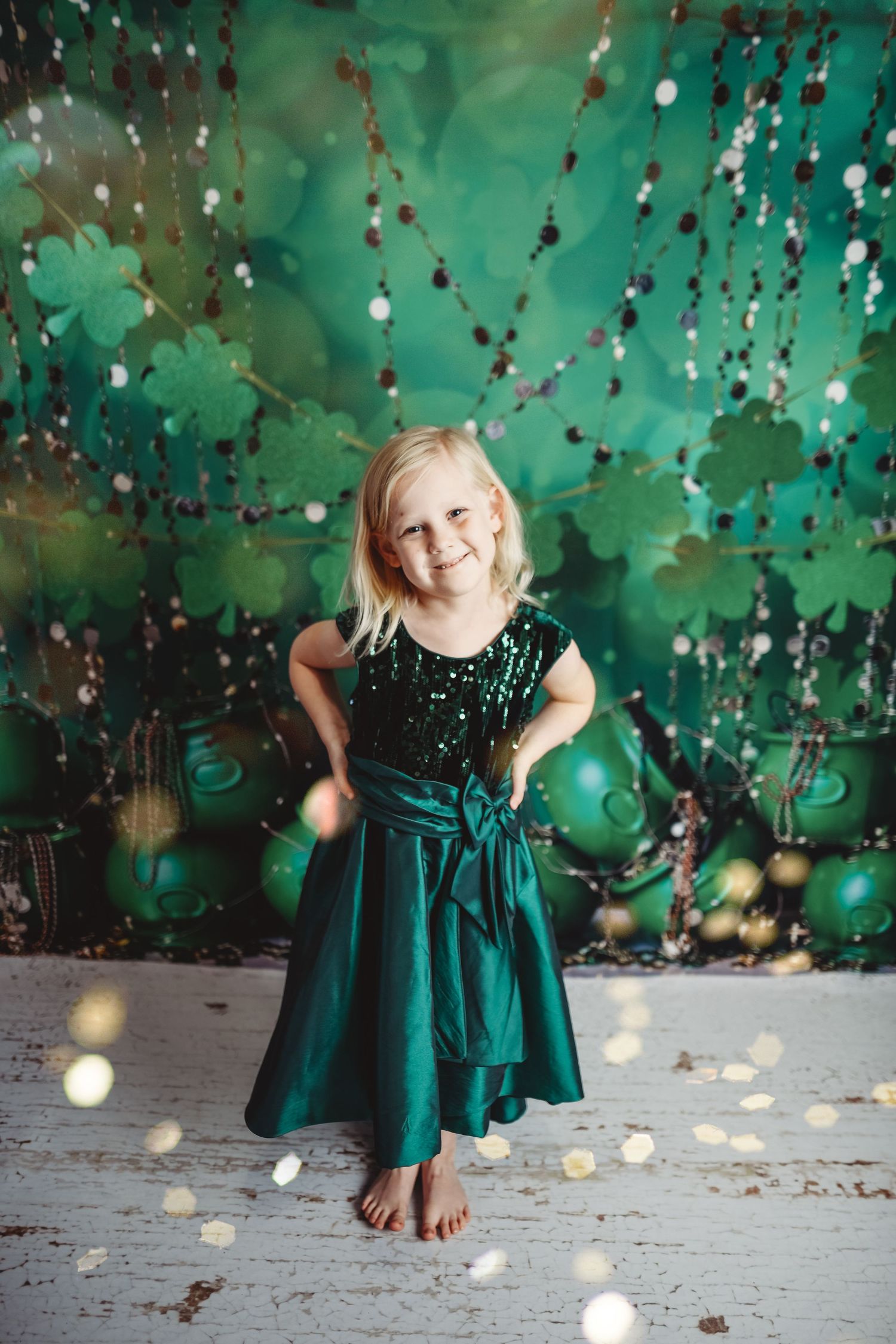 Festive portrait with emerald green dress against sparkly St. Patrick's Day themed backdrop.