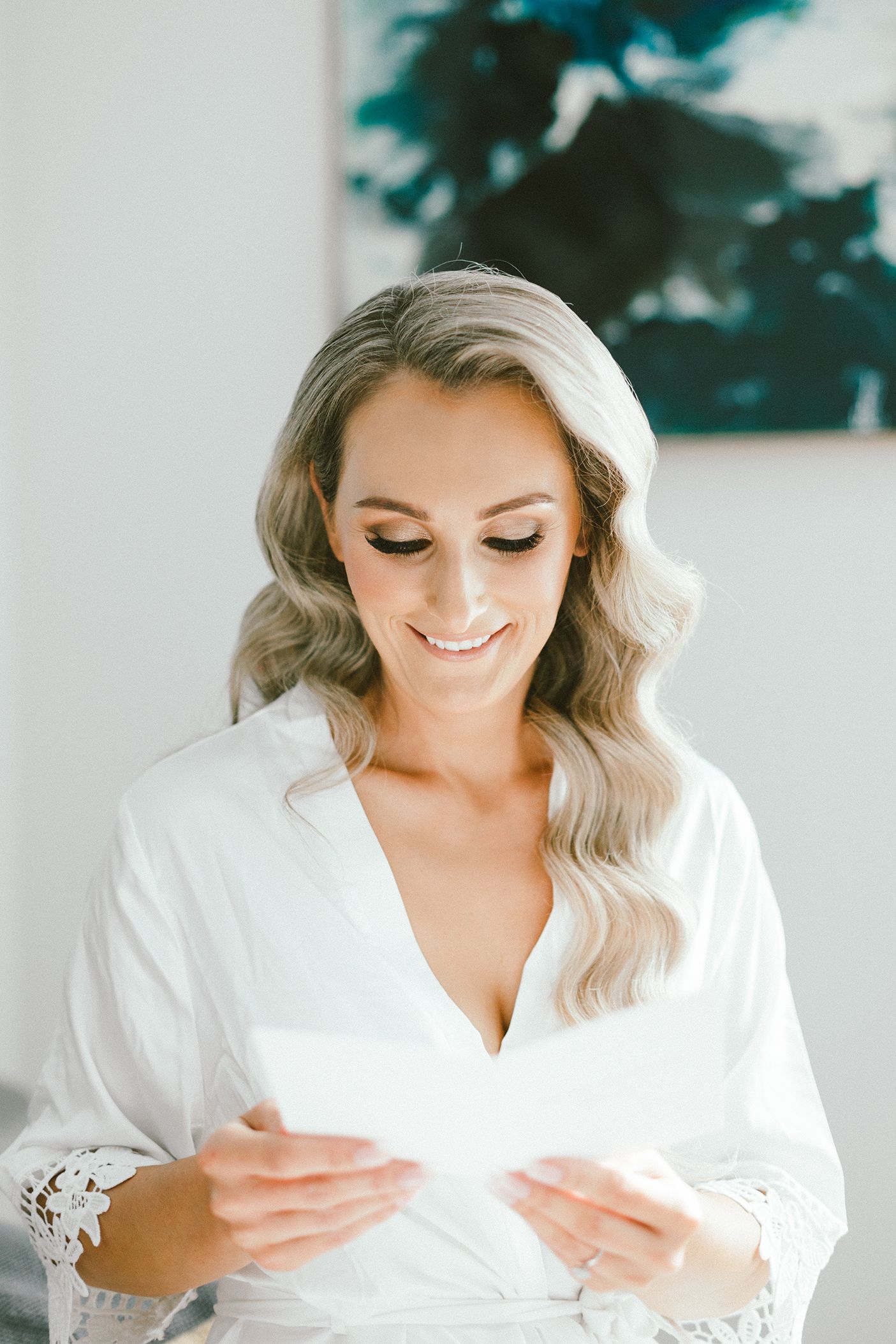 Person in white robe reading paper with elegant styling.