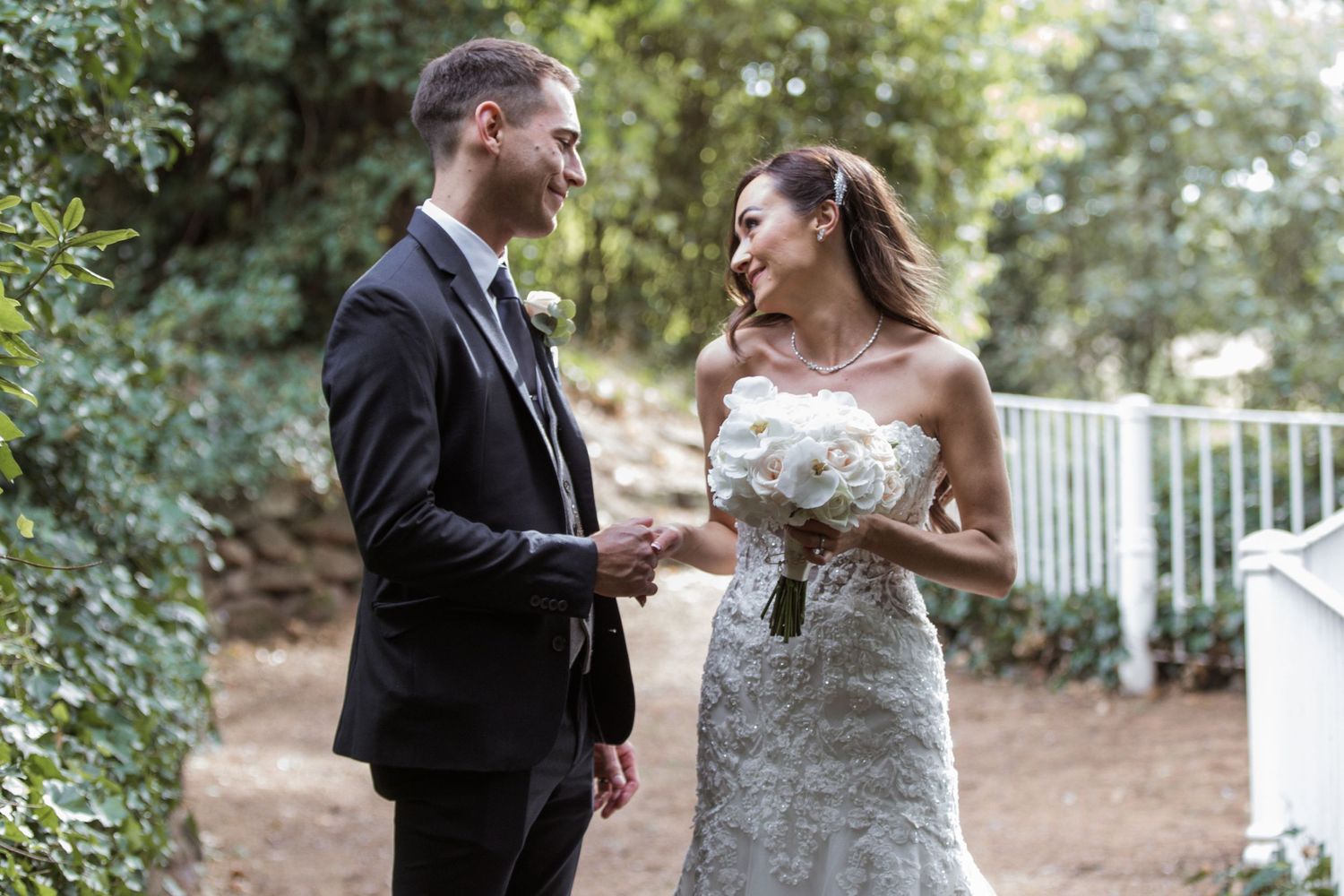 Wedding couple shares joyful laughs while sitting together in an outdoor garden setting.