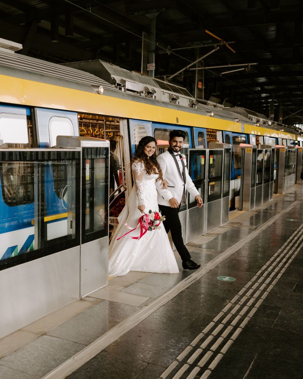 Modern train station platform with couple in formal attire posing for wedding photos.