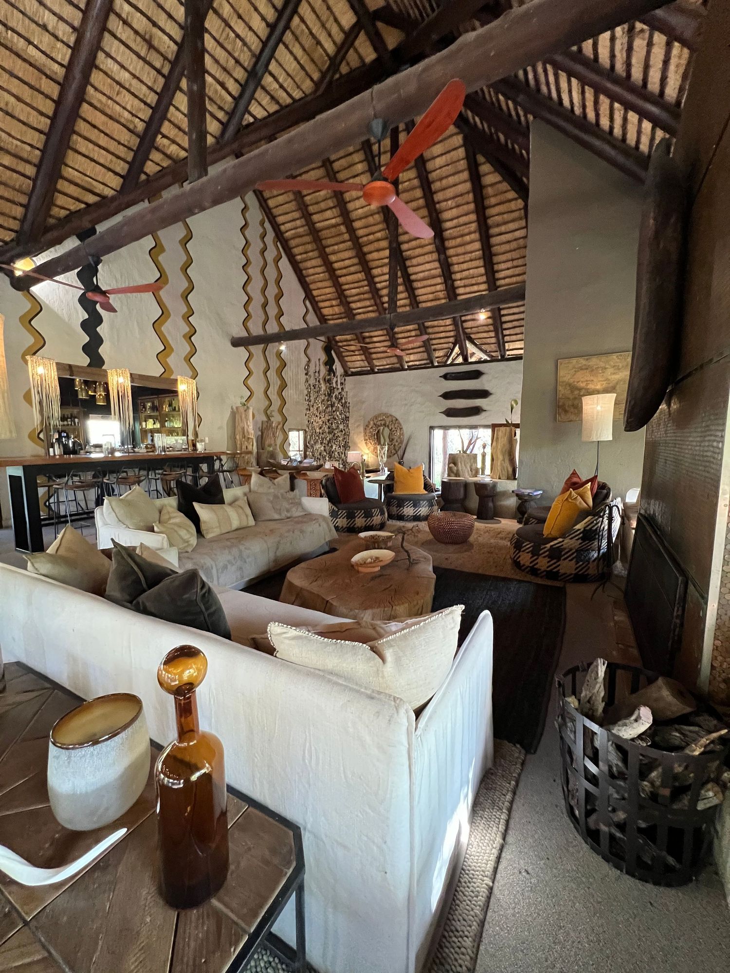 Luxurious safari lodge living room with high thatched ceiling and comfortable white sofas.