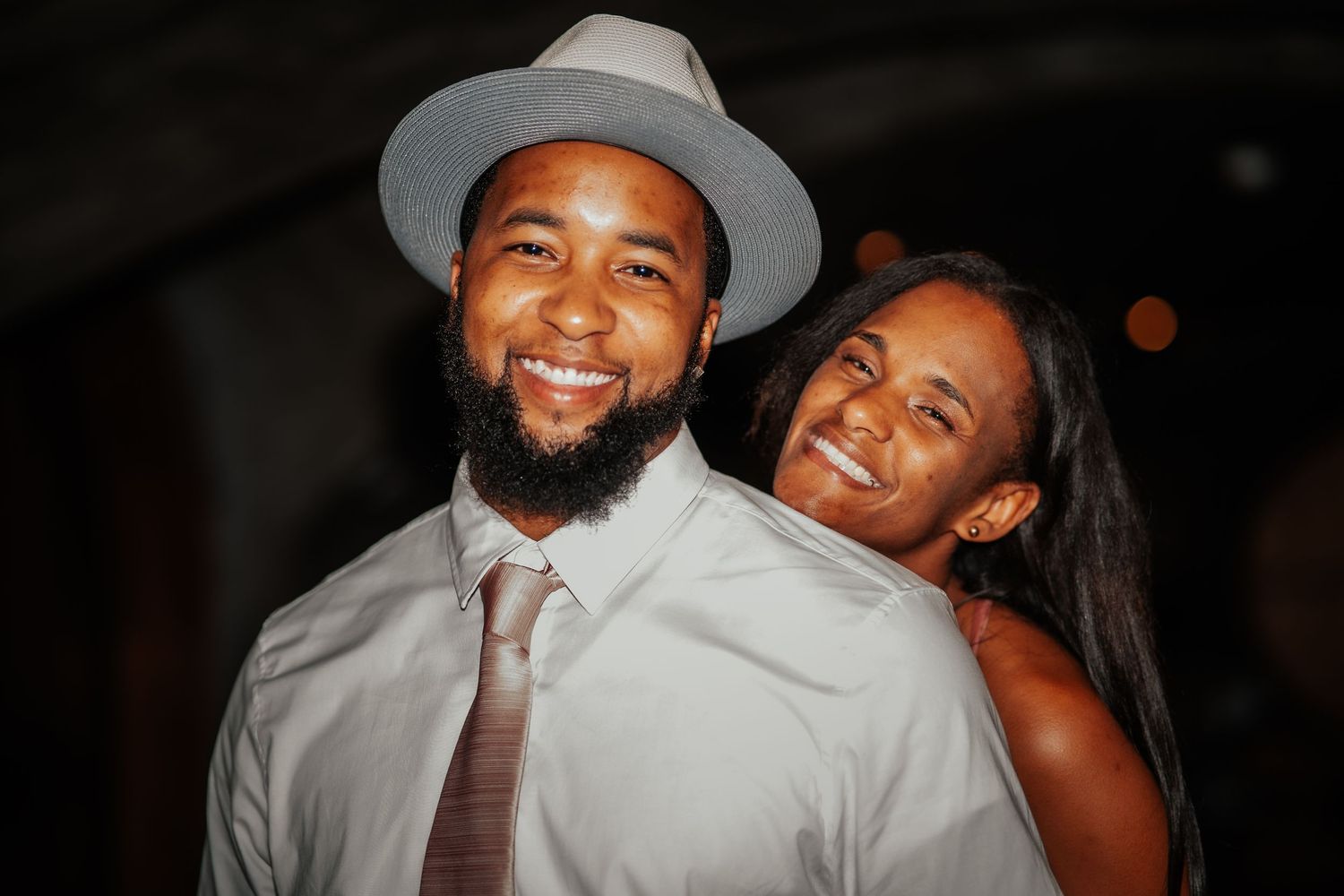 A joyful couple shares a warm embrace and bright smiles during their evening celebration.