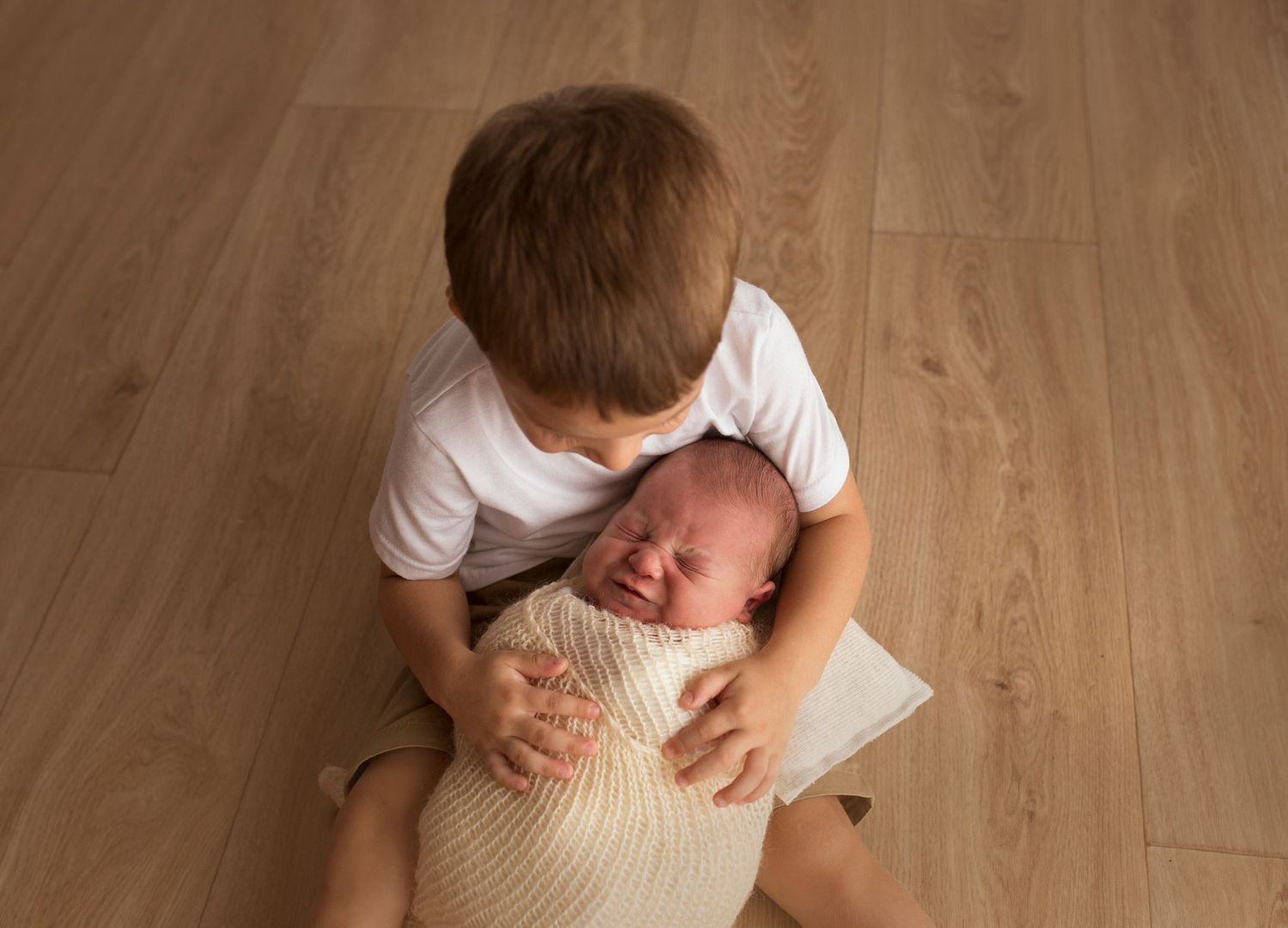 toddler holding crying newborn baby boy
