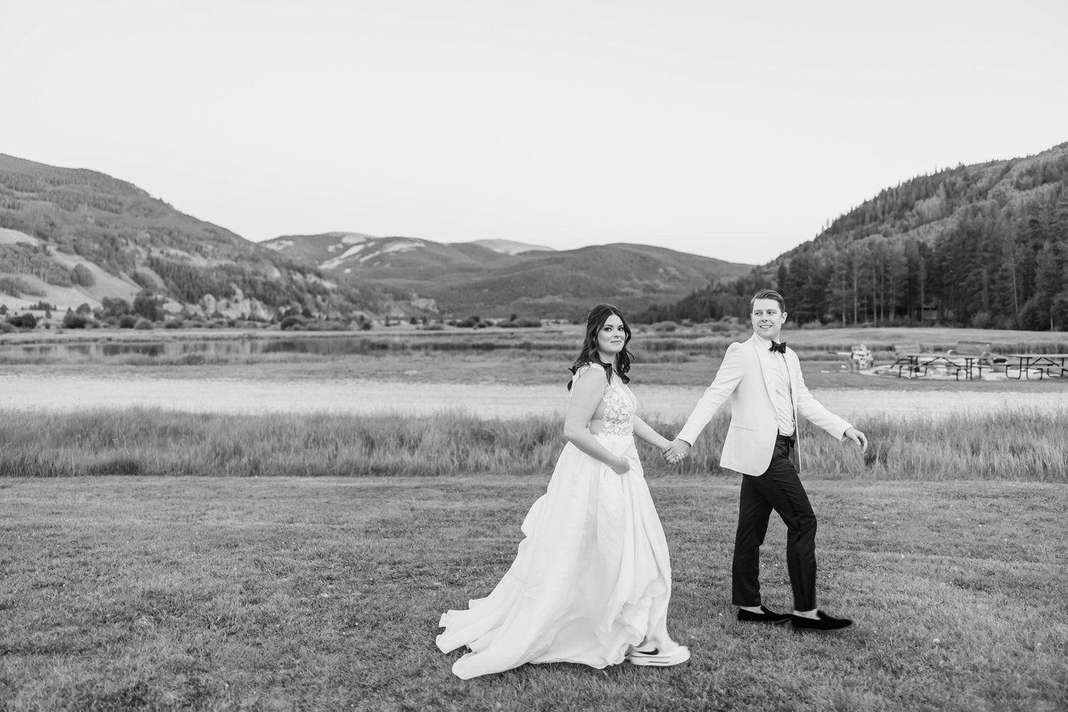 Wedding couple posing in front of scenic mountain landscape with snow-capped peaks.