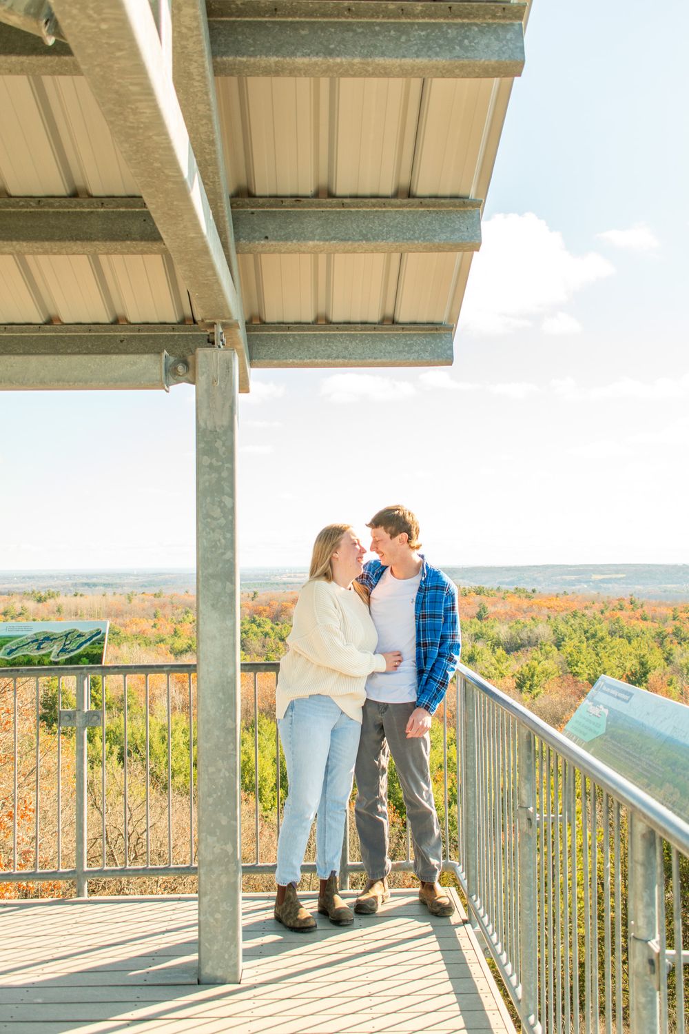 A couple shares an intimate moment on an observation deck overlooking fall foliage.