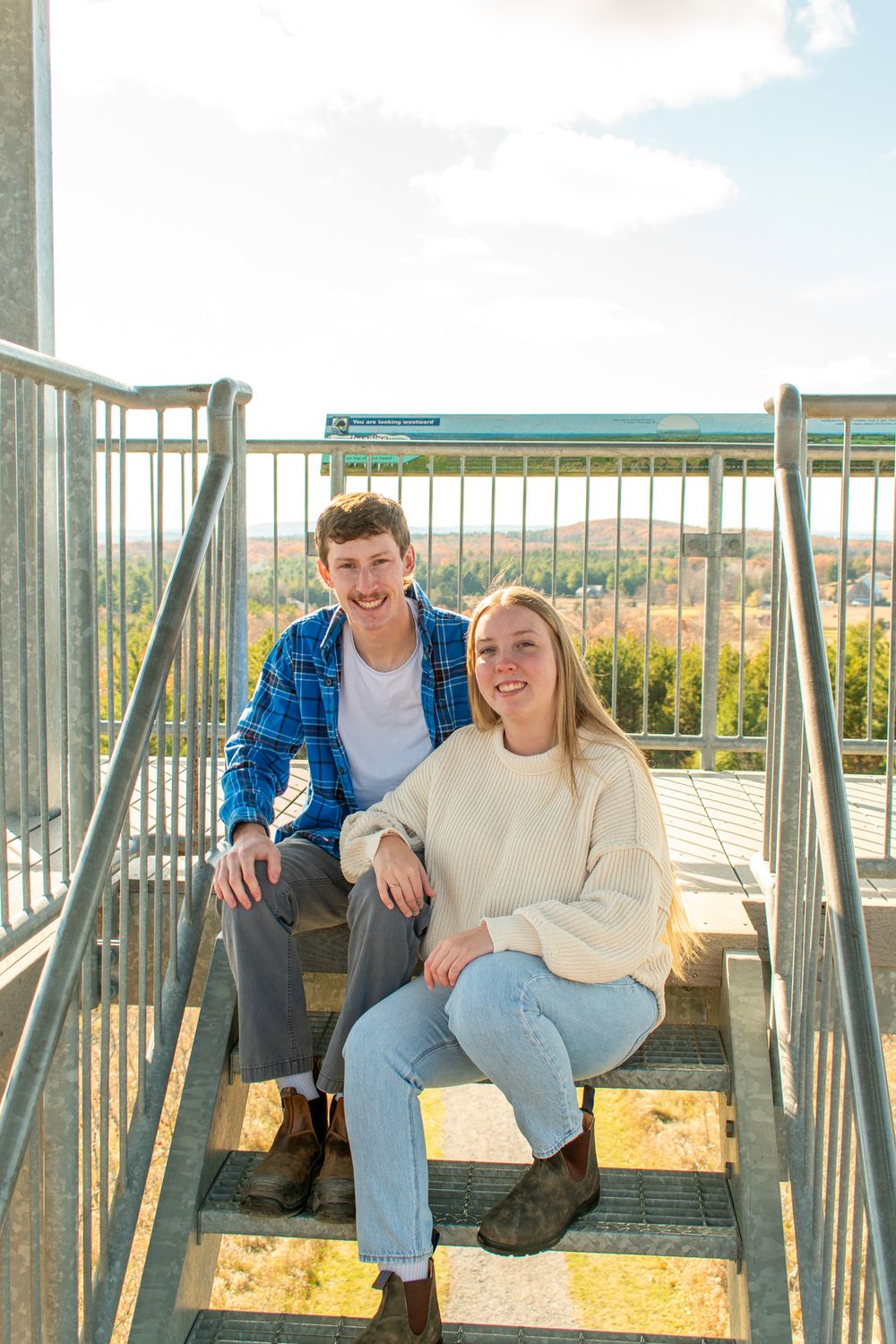 A couple sharing a sweet moment together while sitting on metal stairs on a sunny day.