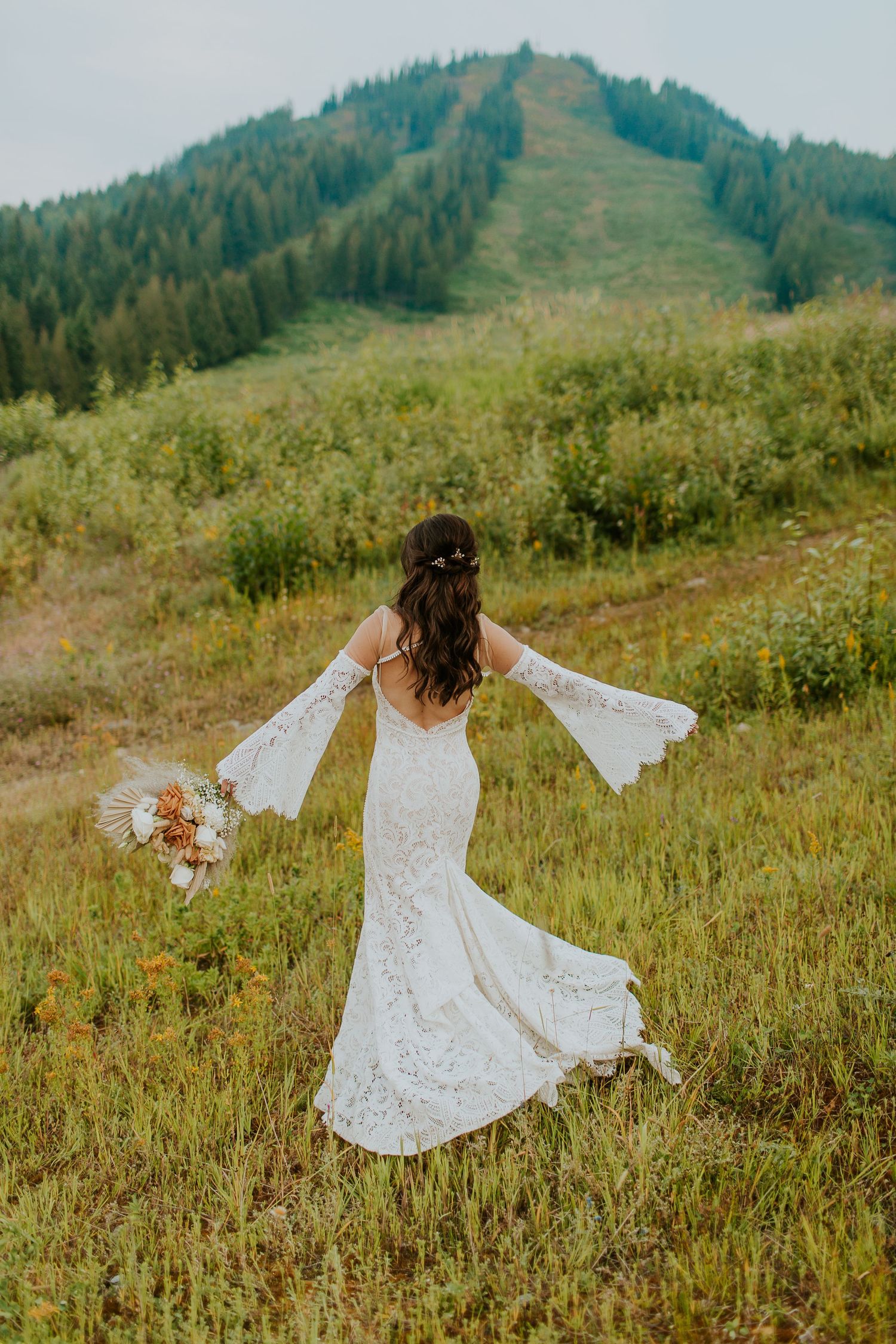 A bride twirls in a mountain field on Red Mountain Resort BC