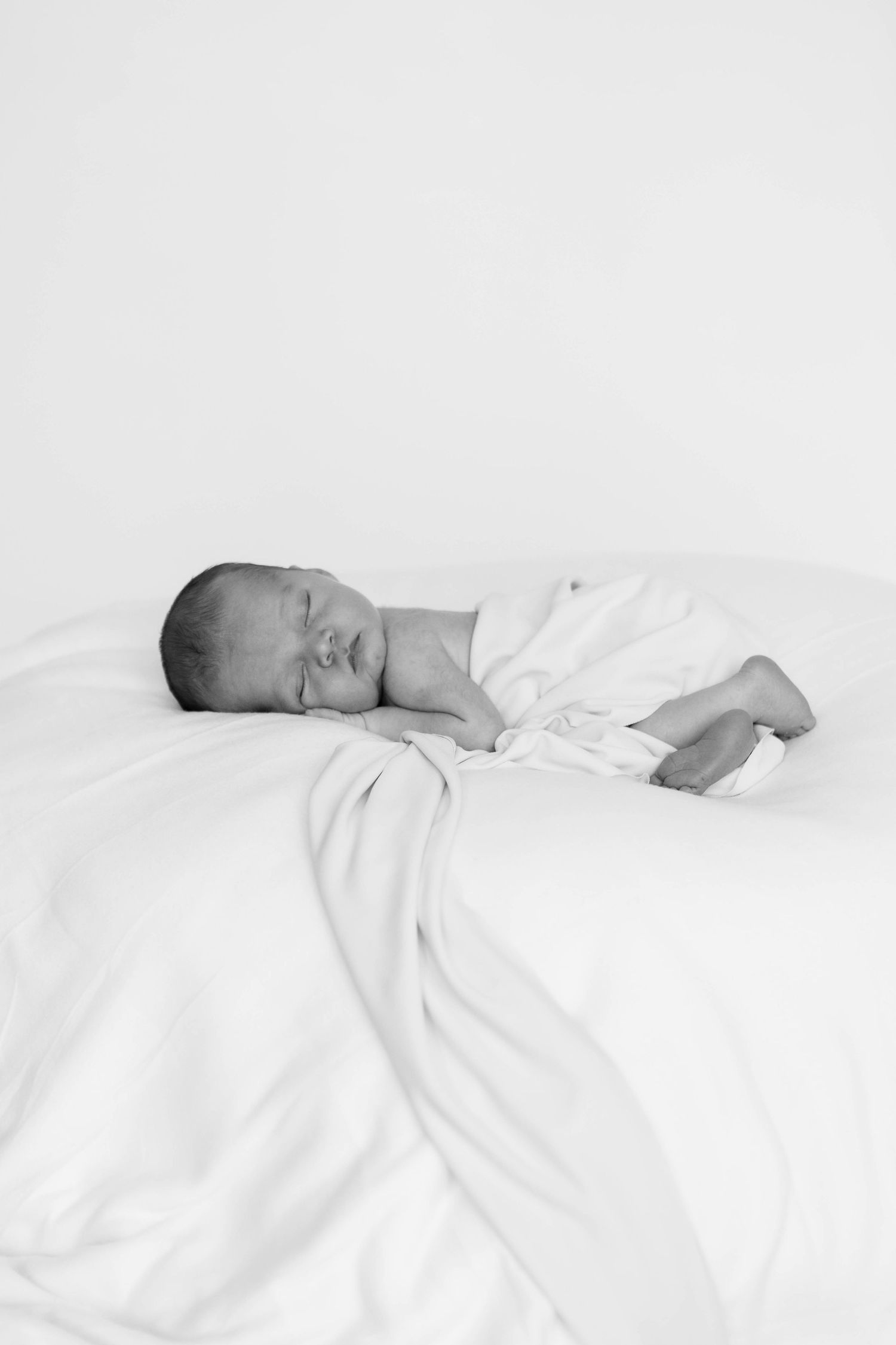 newborn baby asleep in posed position. Black and white image of baby during his newborn session in the studio