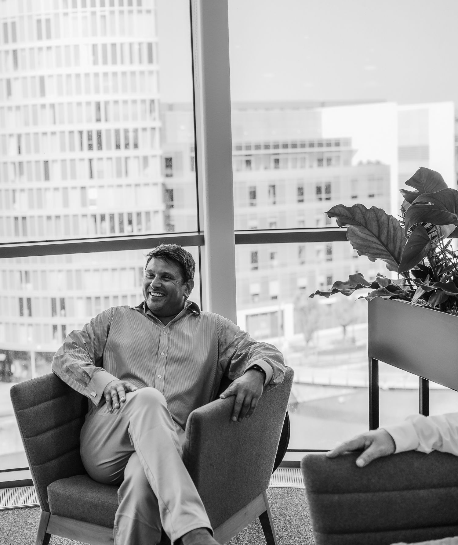 Black and White images of a man sitting comfortable in an office setting, naturally laughing.