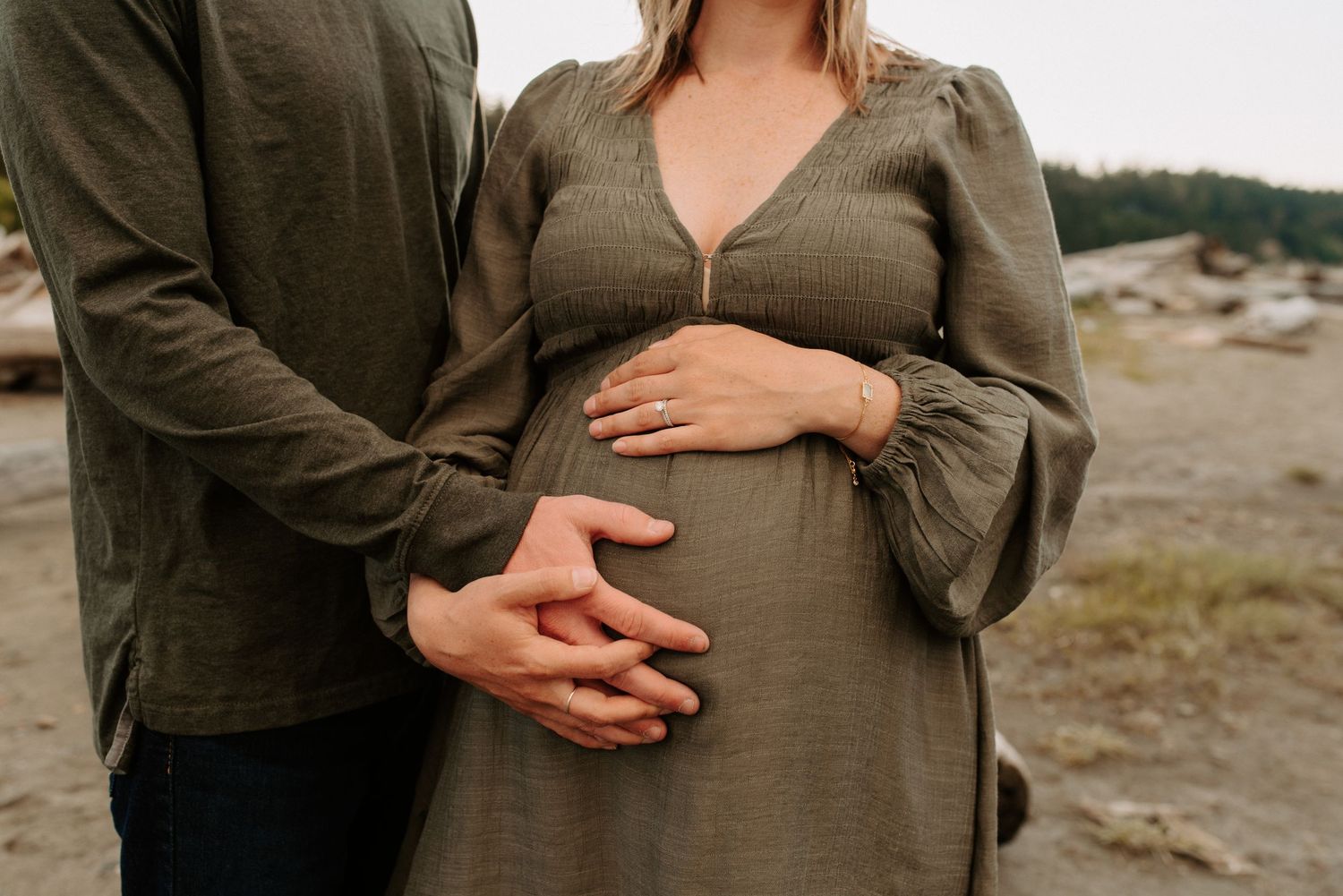 Couple in casual attire embracing during outdoor maternity photoshoot.