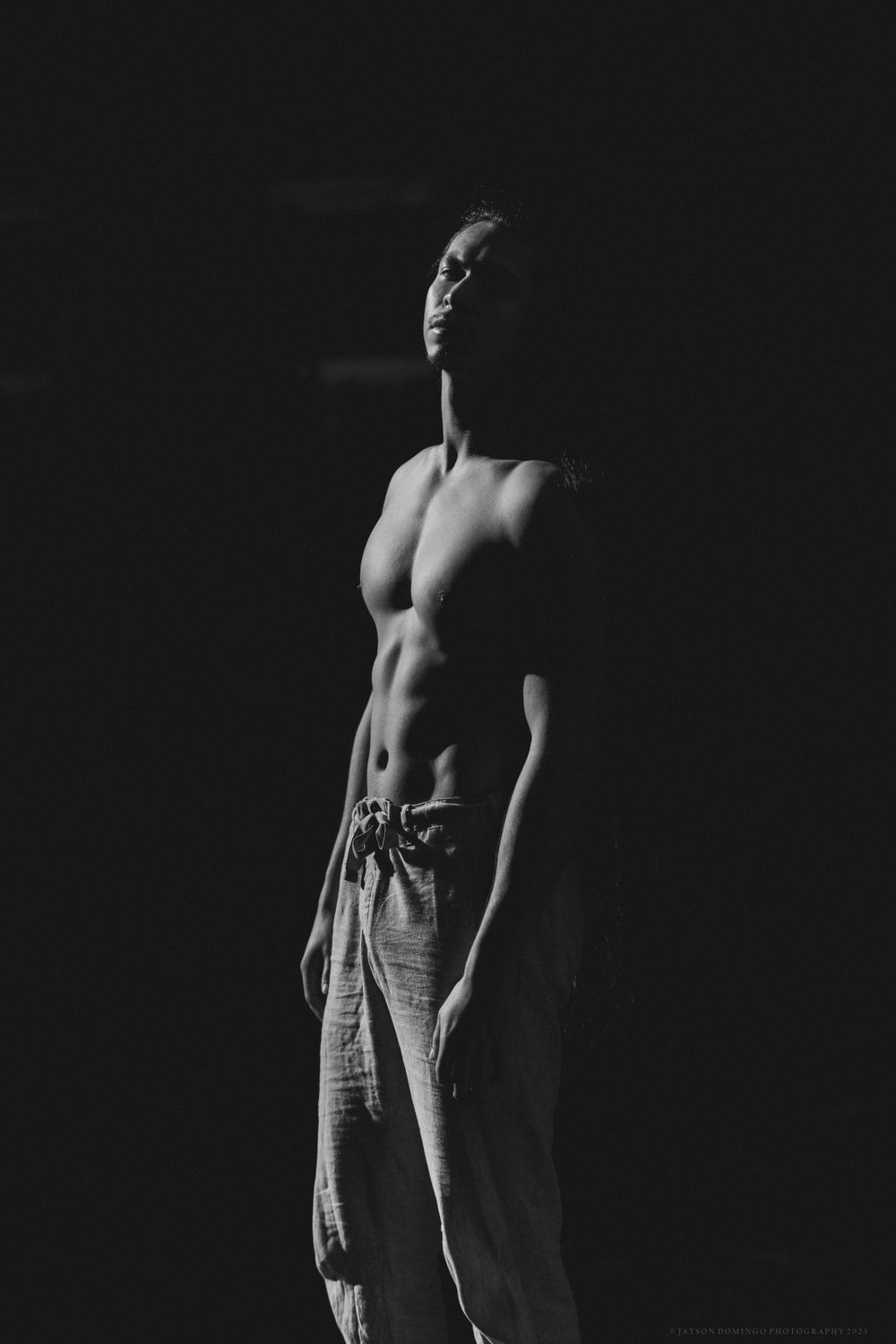 Artistic black and white portrait showing muscular physique in dramatic lighting.