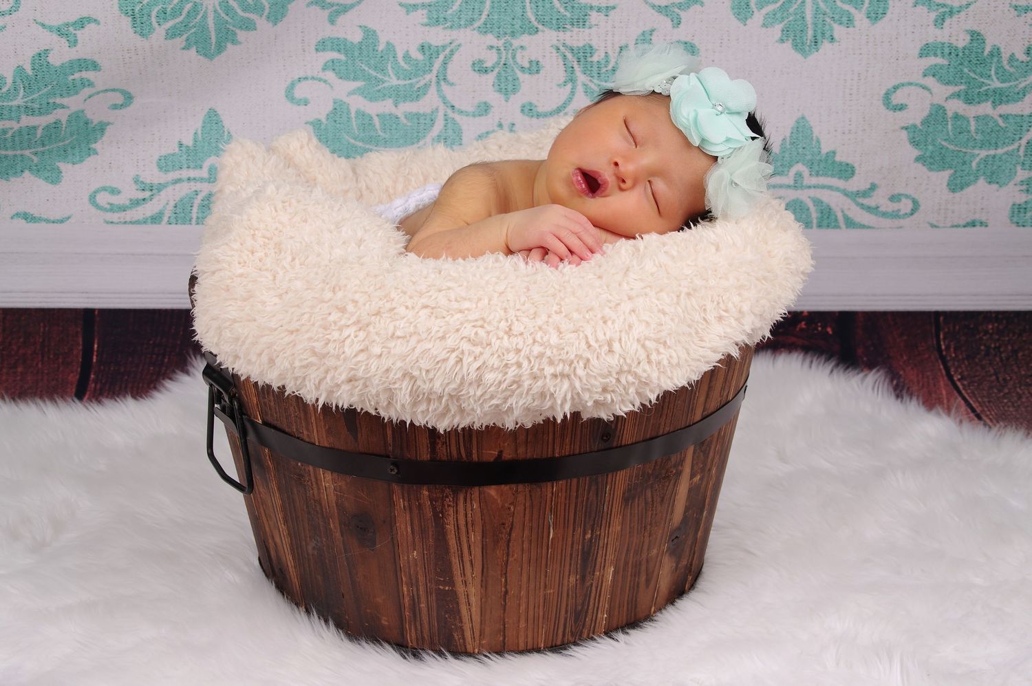 newborn baby girl sleeping in bucket mint backdrop