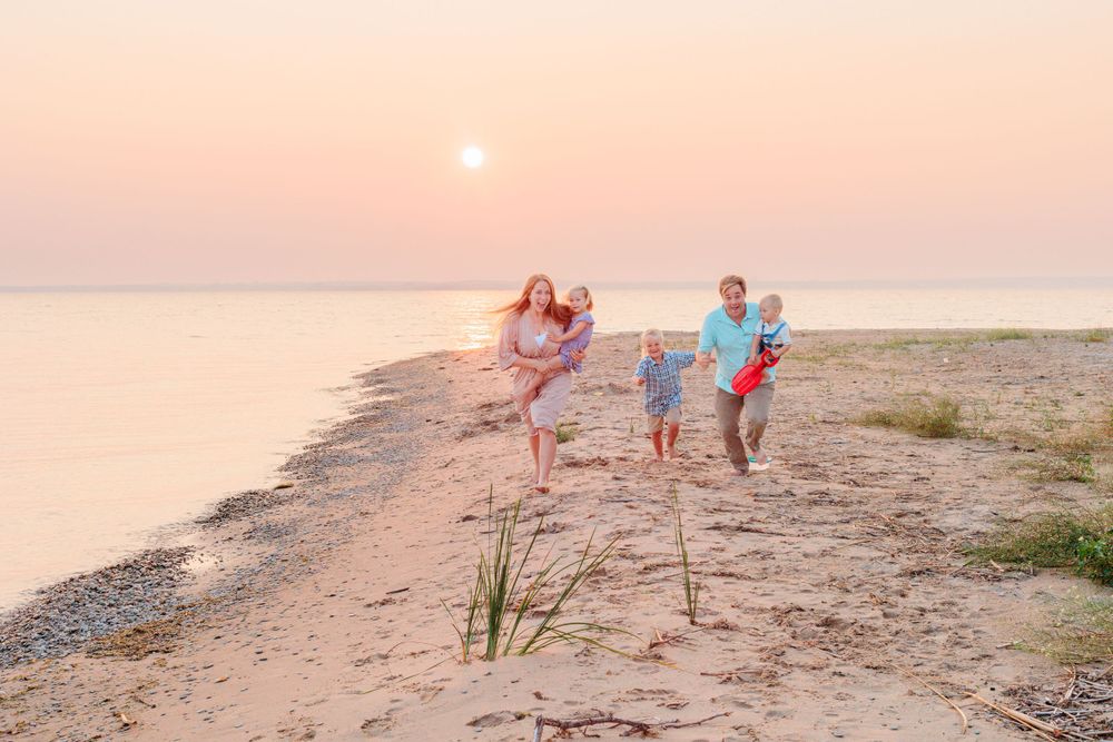 Playful family portraits on the beach at sunset