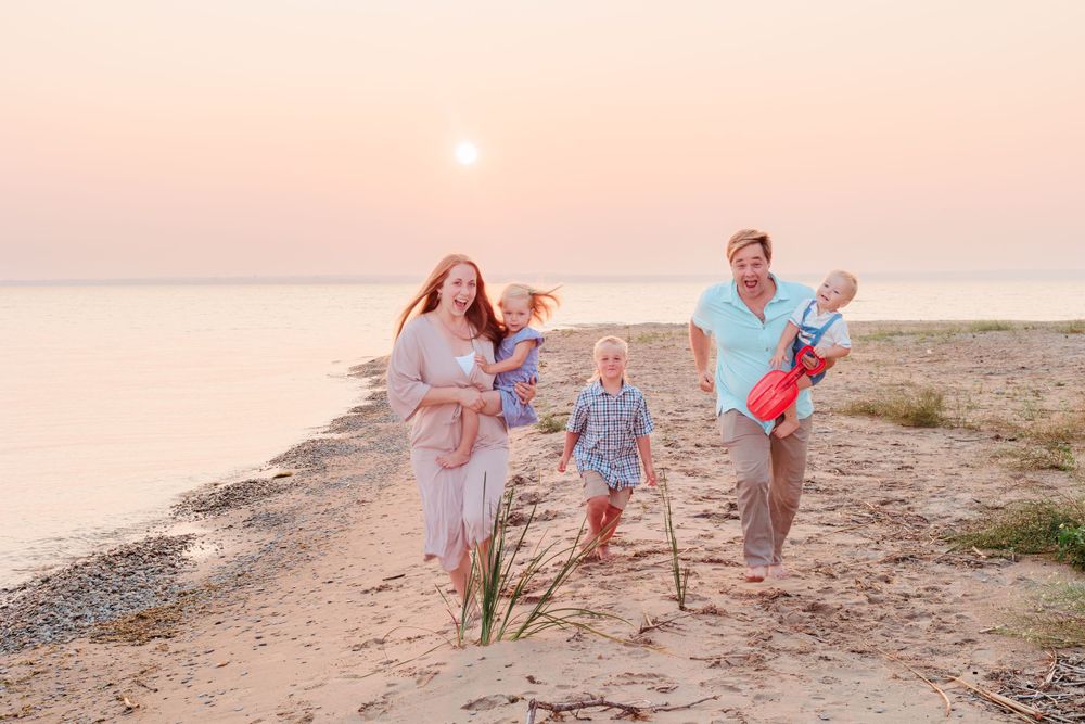 Playful family portraits on the beach at sunset