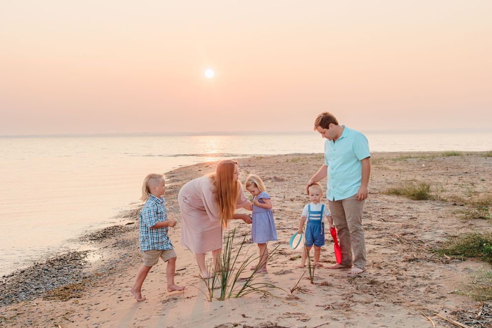 Playful family portraits on the beach at sunset