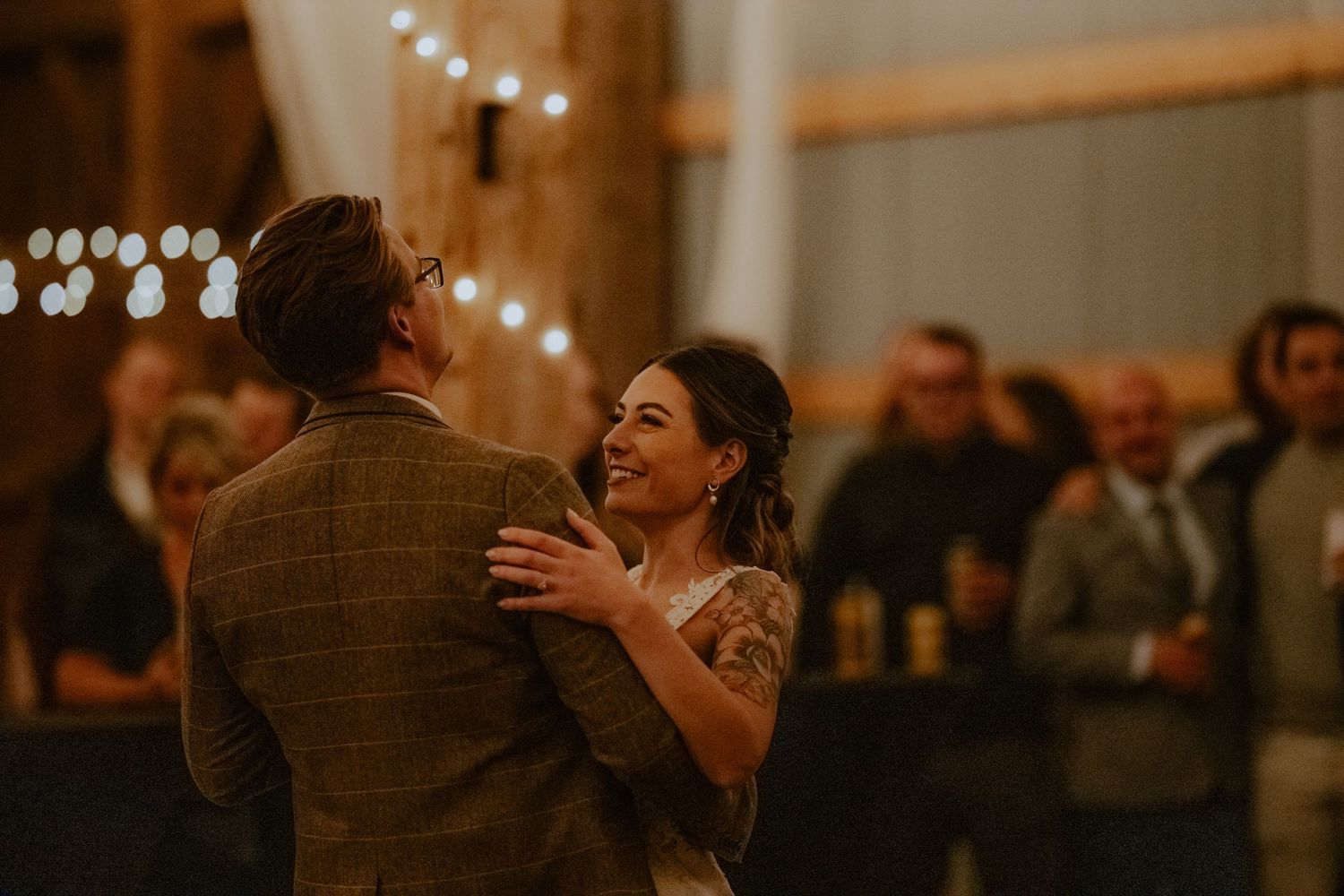 a bride and groom share their first dance in a dimly lit barn