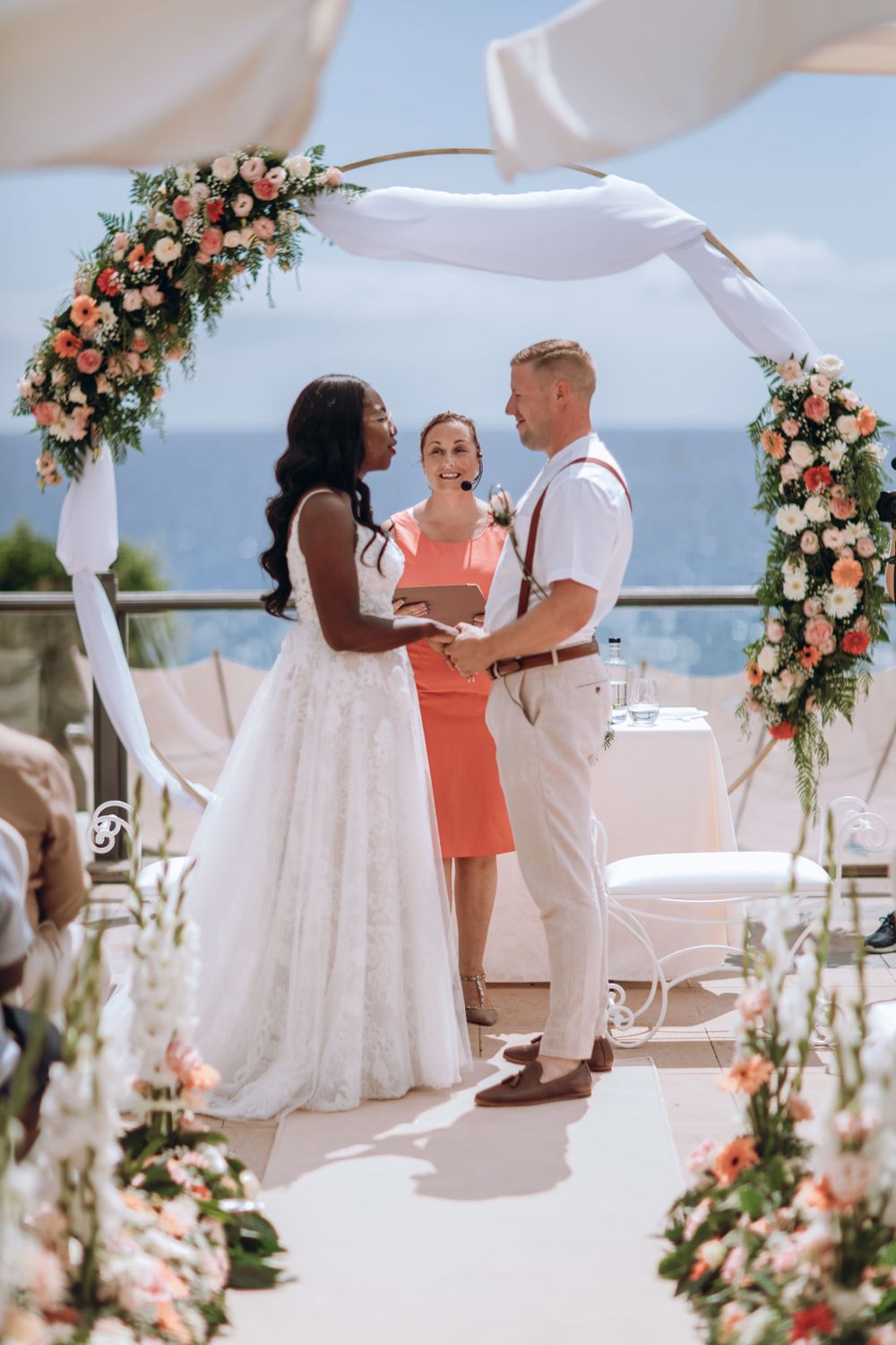 Wedding ceremony photograph of bride, groom and celebrant under a flower arch in Iberostar Anthelia, Tenerife.