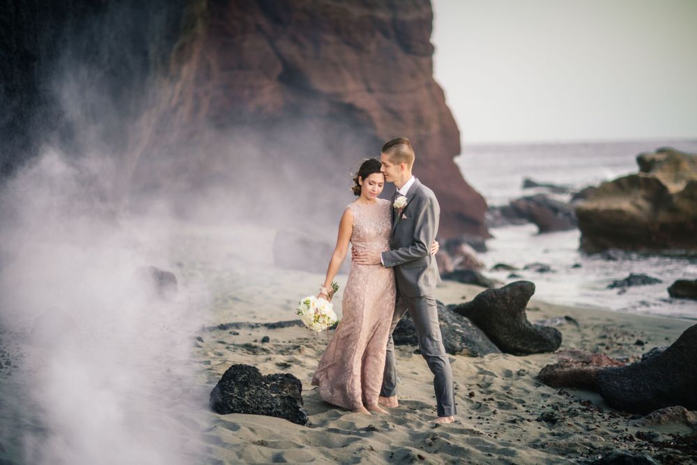 Bride and groom portrait, wide angle, cinematic on a wild beach in Tenerife.