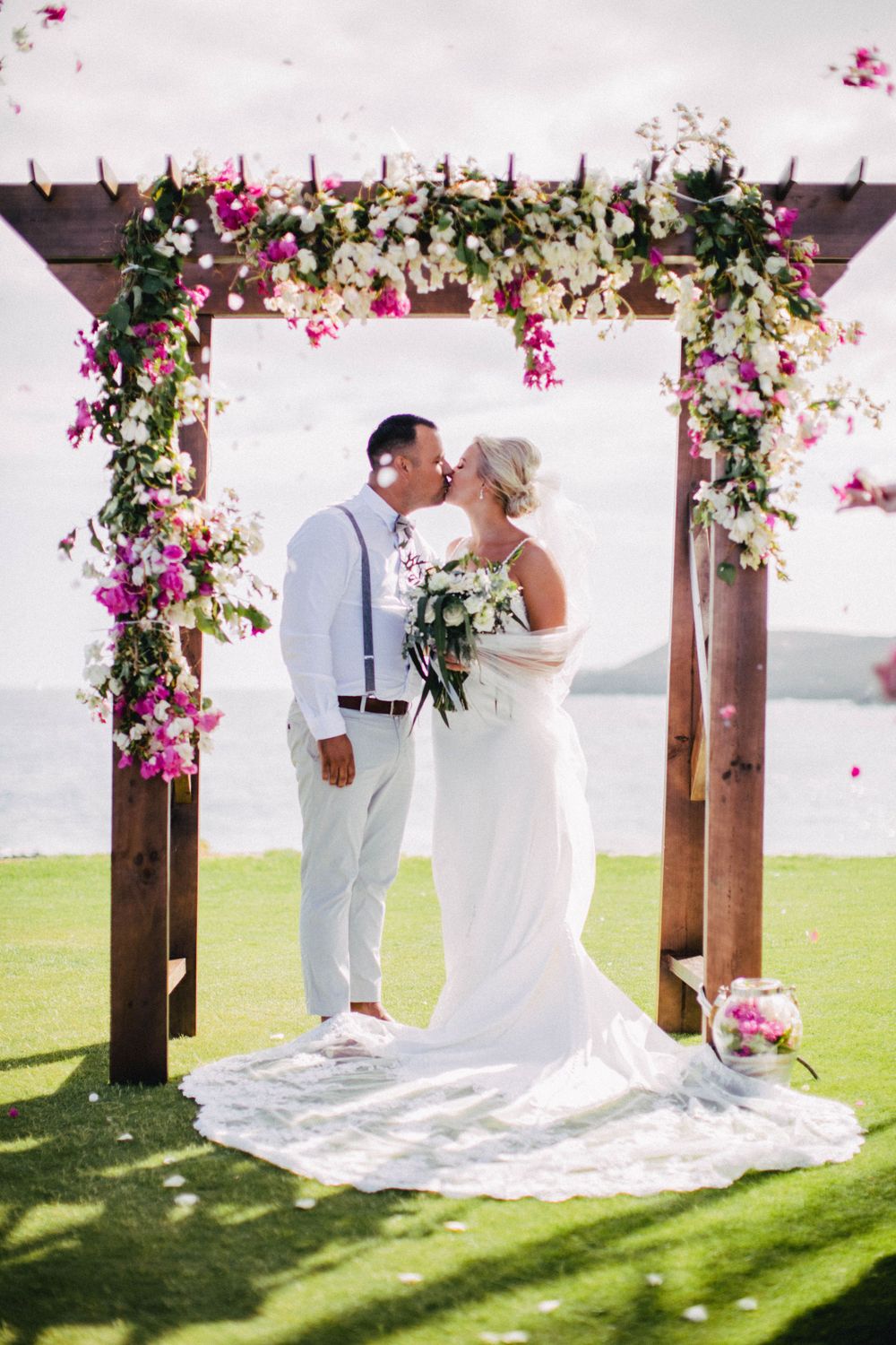 Photograph of bride and groom smiling under a flower arch in Tenerife with beautiful light.