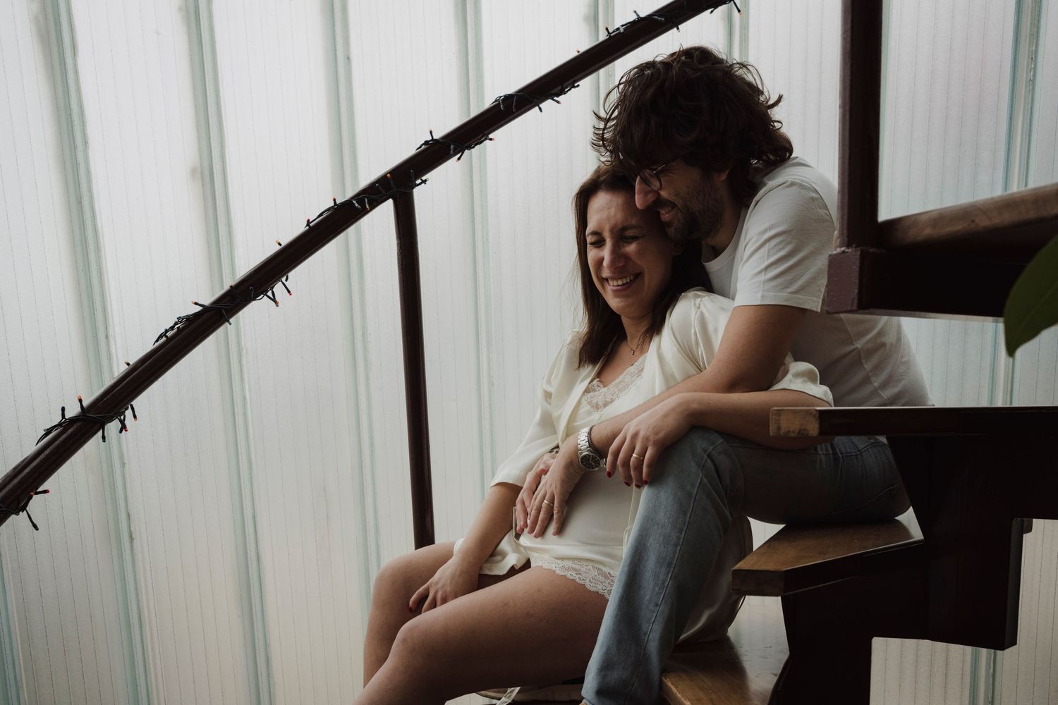 Intimate moment captured on wooden stairs during indoor maternity session.