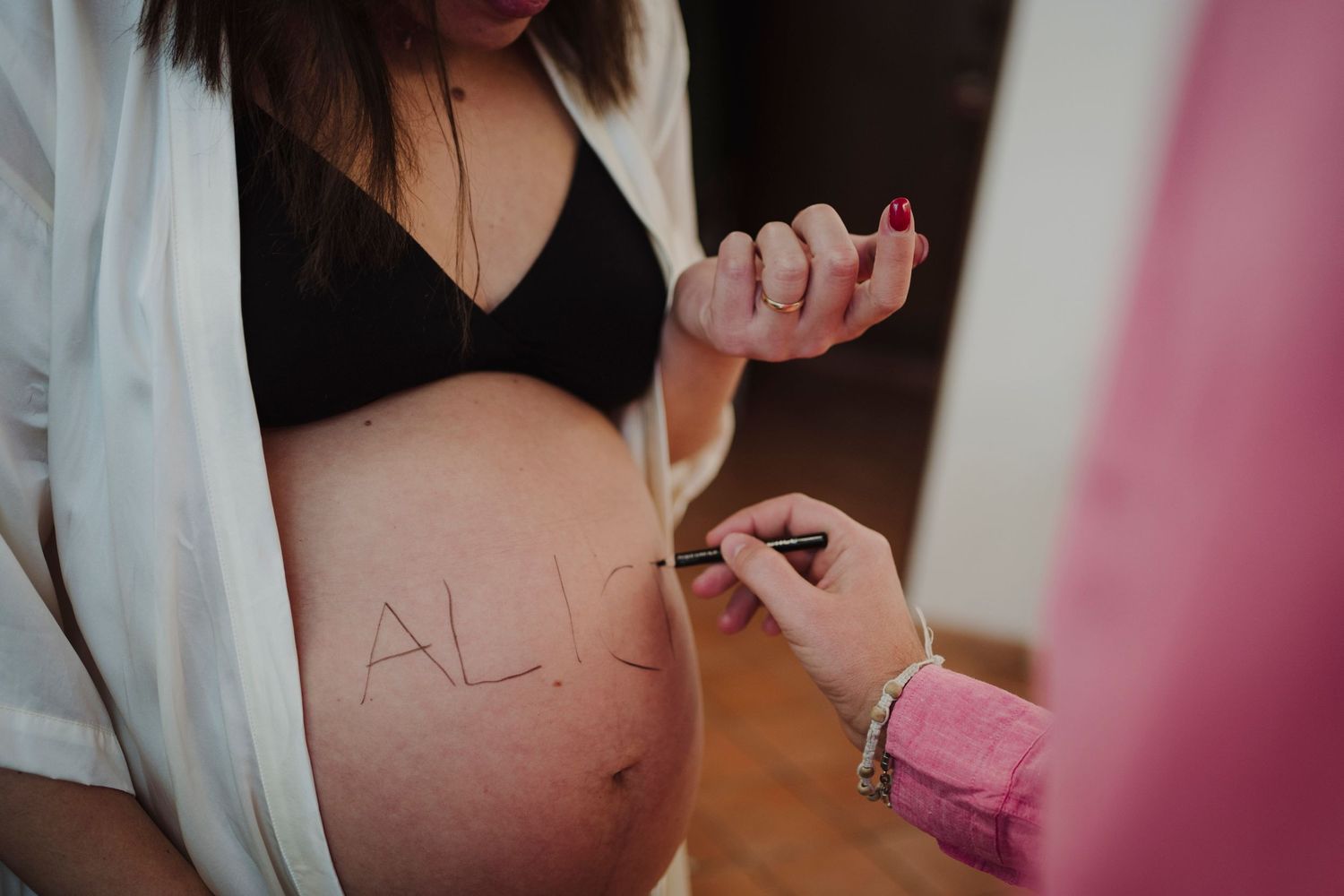 Writing on a pregnant belly in a tender maternity moment.