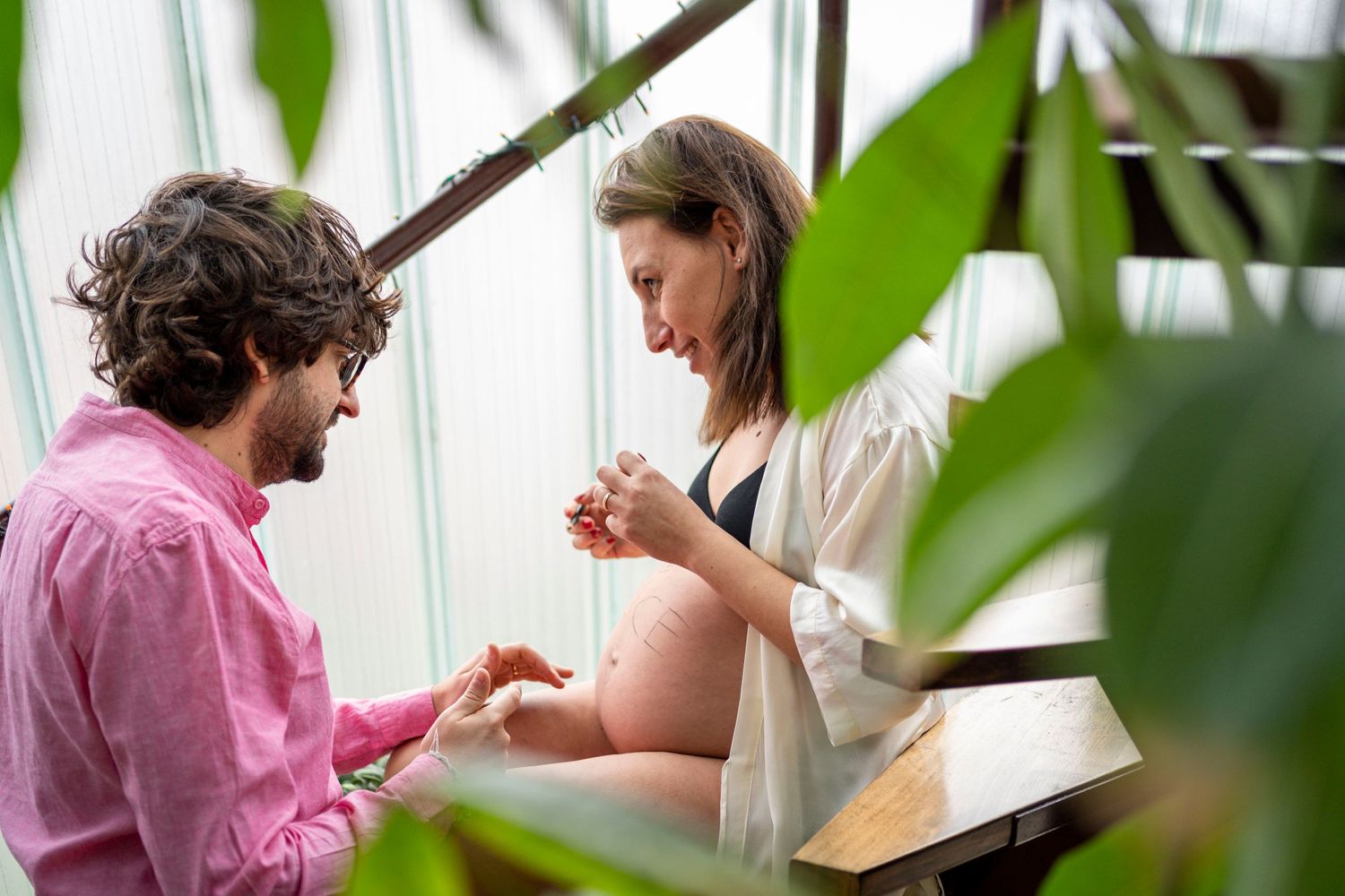 A maternity photo session with plants framing the scene.