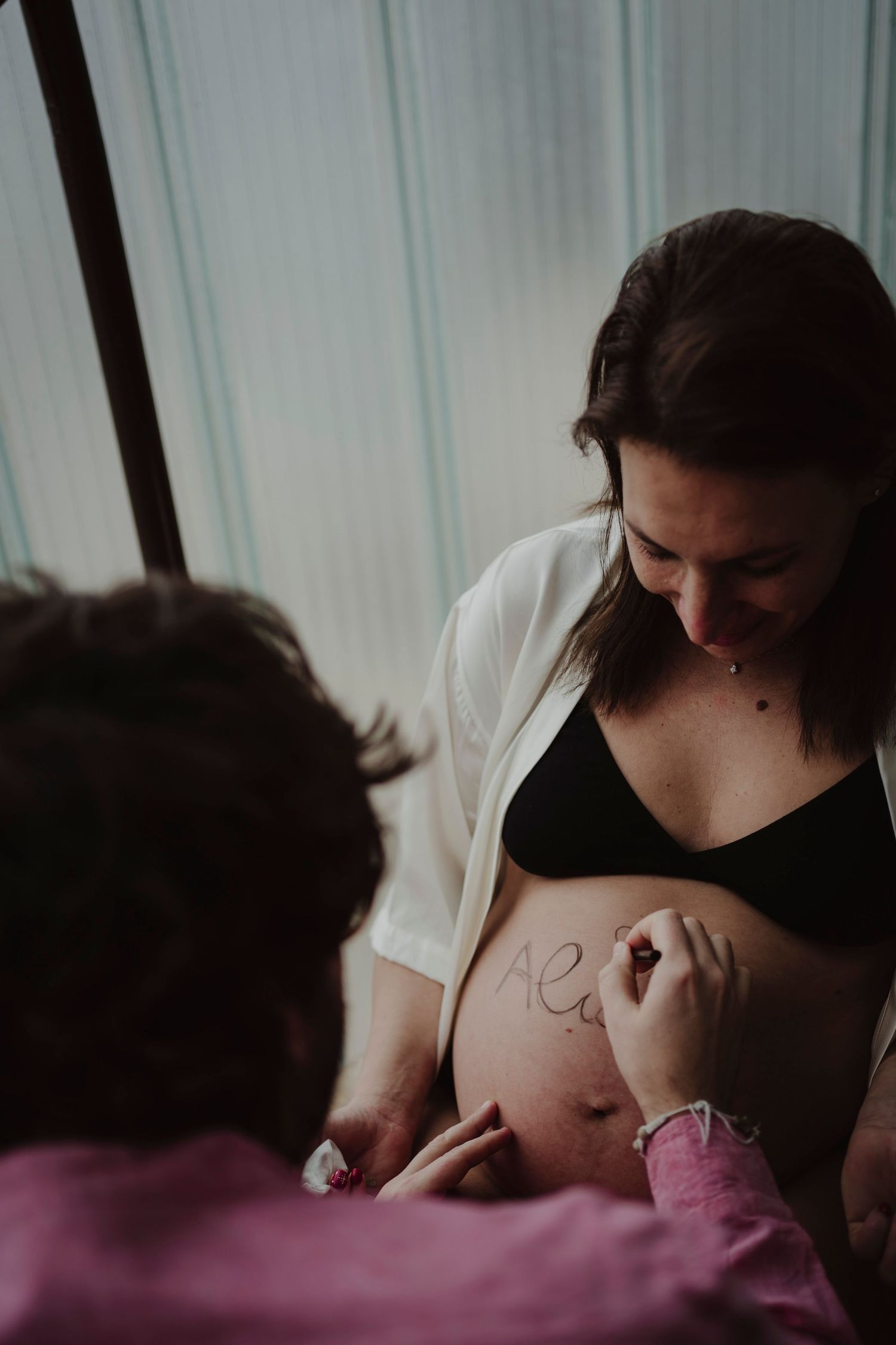 A close-up shot of writing being drawn on a pregnant belly.