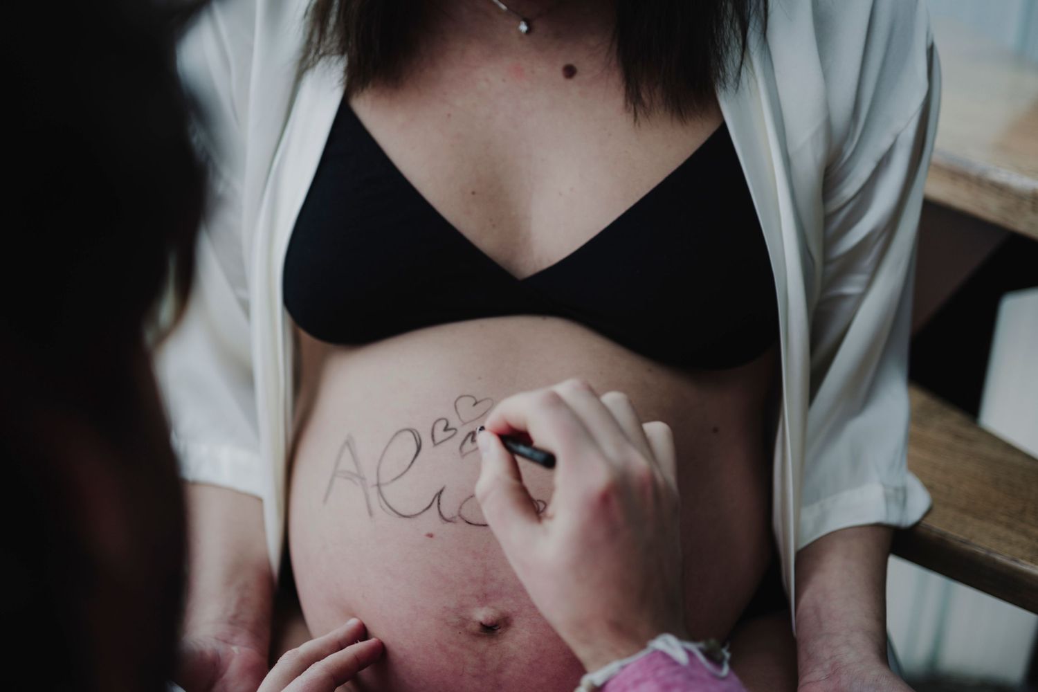 An artistic black and white maternity photo showing writing on a belly.