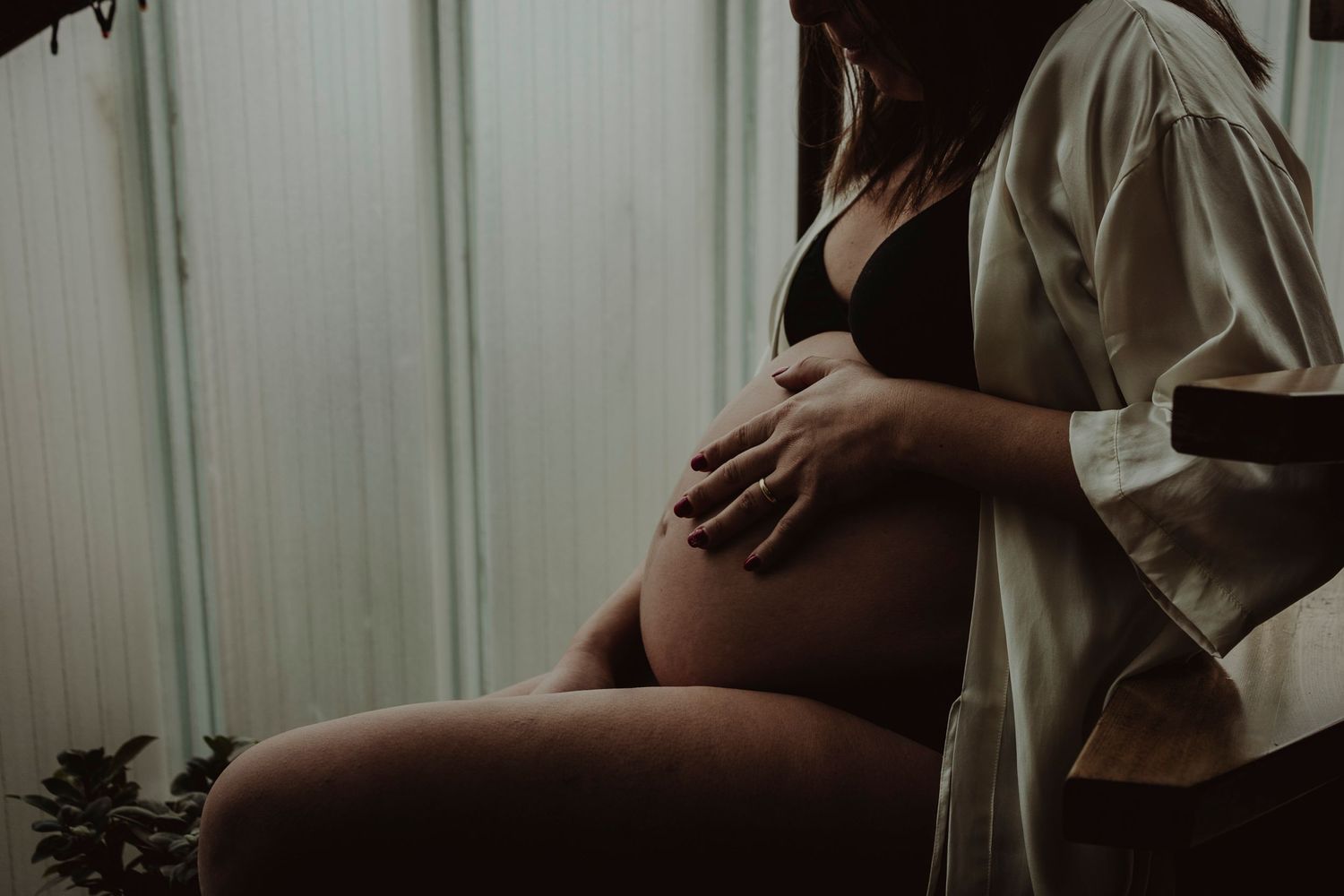 An artistic maternity photo showing a pregnant belly in moody lighting.