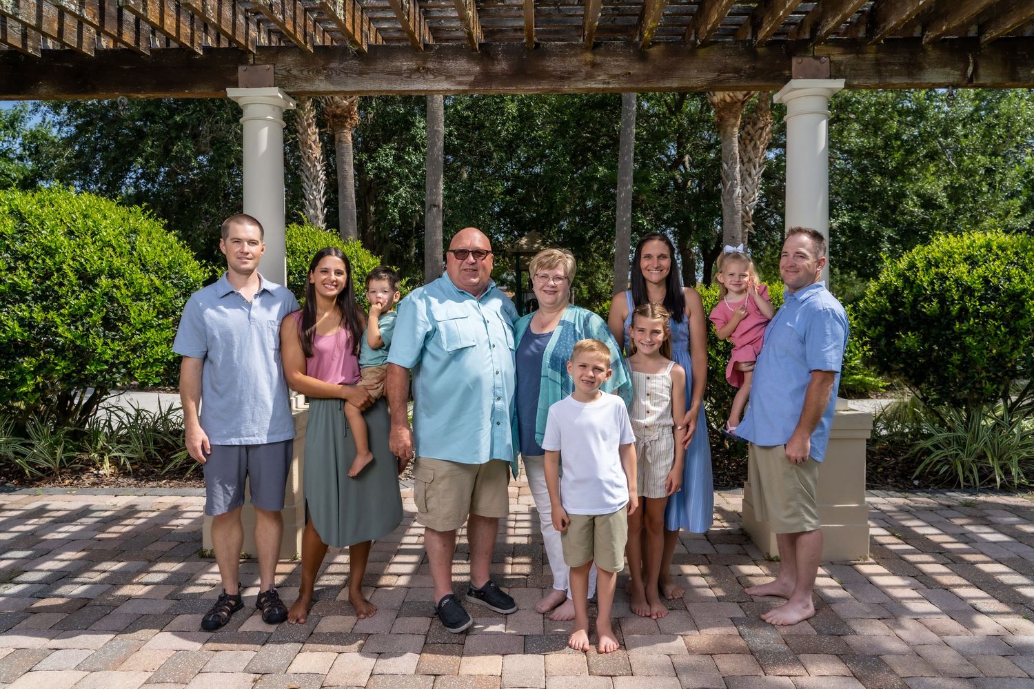 Small group poses under pergola in garden setting for formal photo.