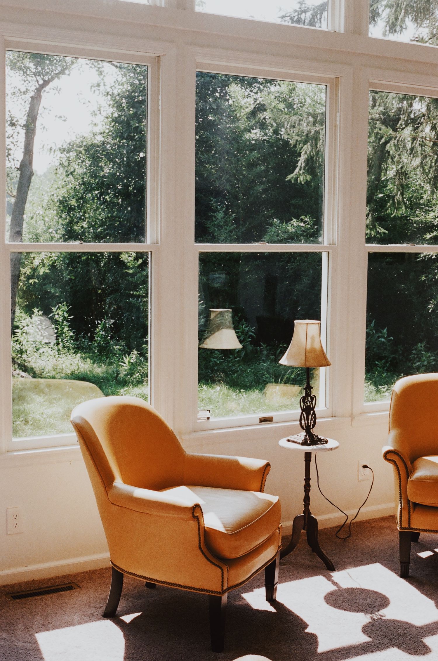Bright sunroom featuring orange chaise lounges and large windows with natural light streaming in.