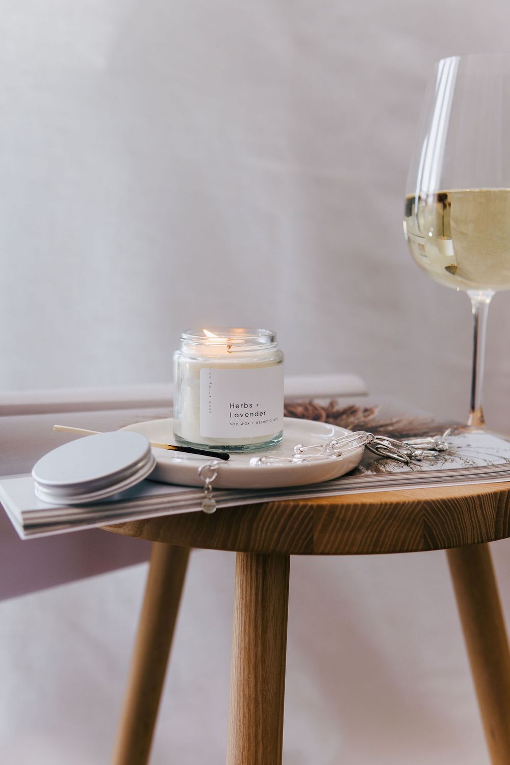 Minimalist table setting with lit candle, wine glass and wooden accent table.