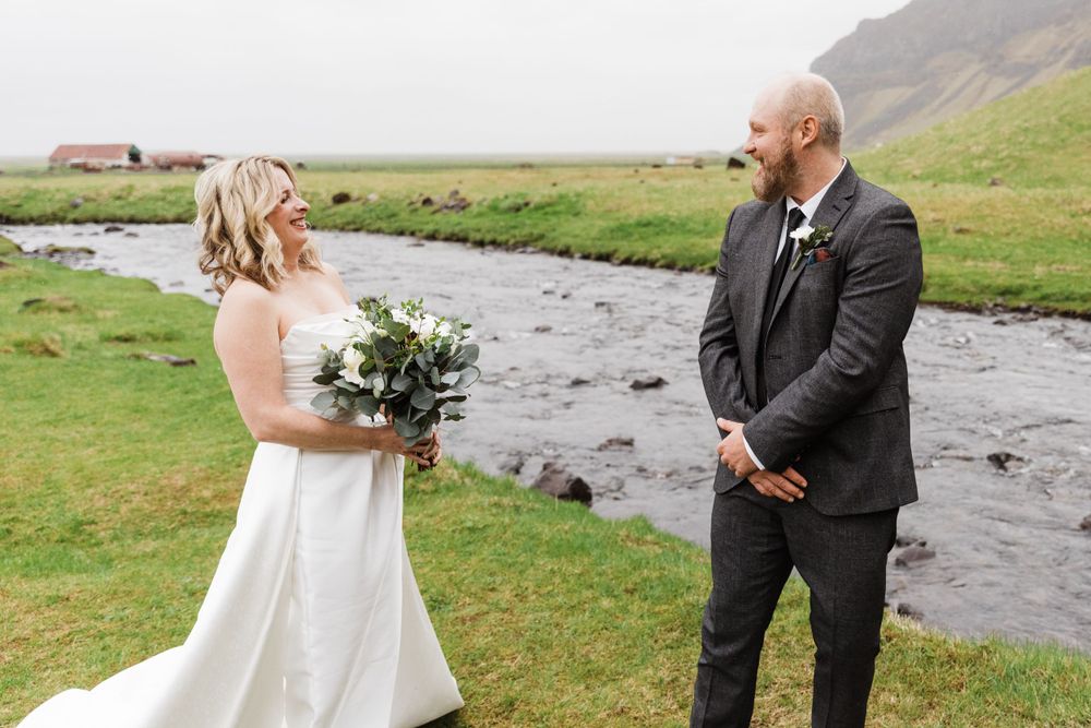 Emotional exchange between couple during outdoor wedding ceremony by flowing river.