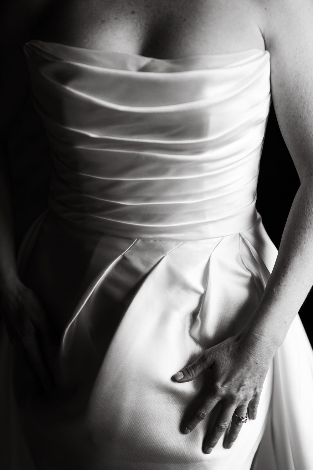 Detail shot of a white wedding dress showing pleated fabric texture and elegant draping.