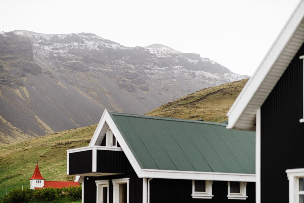 Black and white Nordic-style houses with green roofs against a mountainous backdrop.