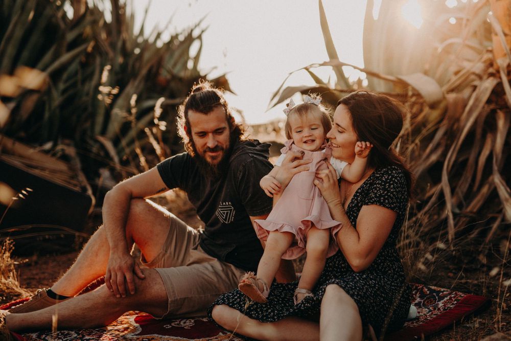 Warm sunlit scene of family bonding outdoors among tropical foliage.