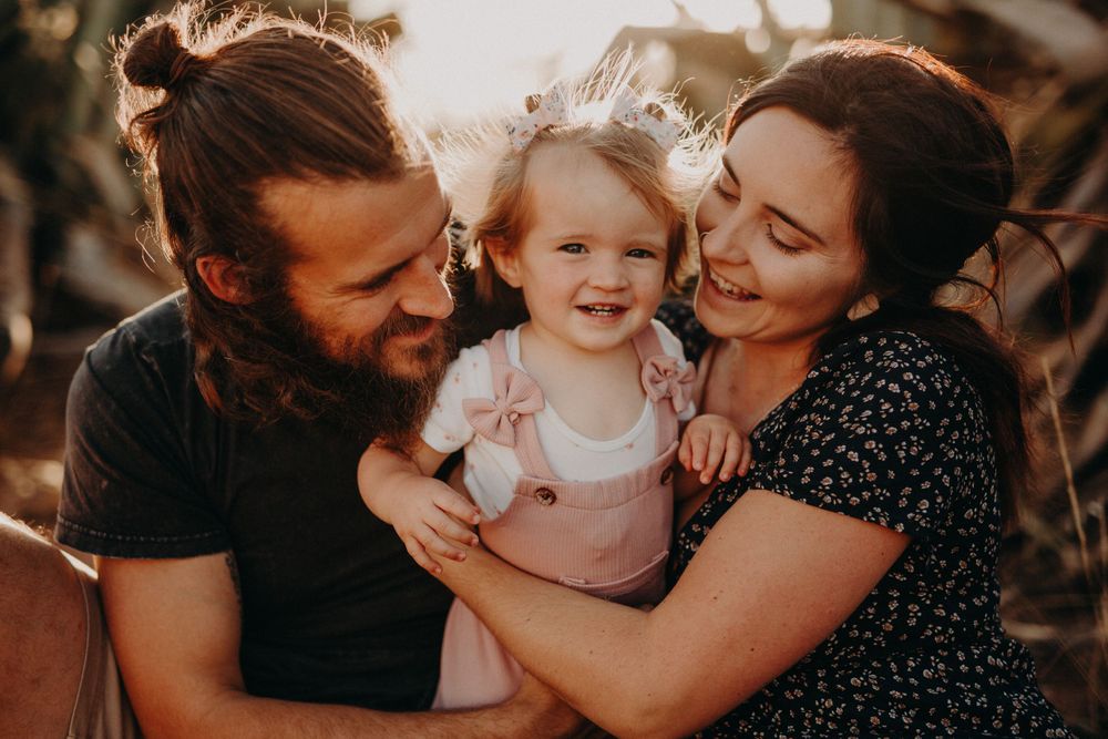 Tender family moment photographed against natural scenery at sunset.
