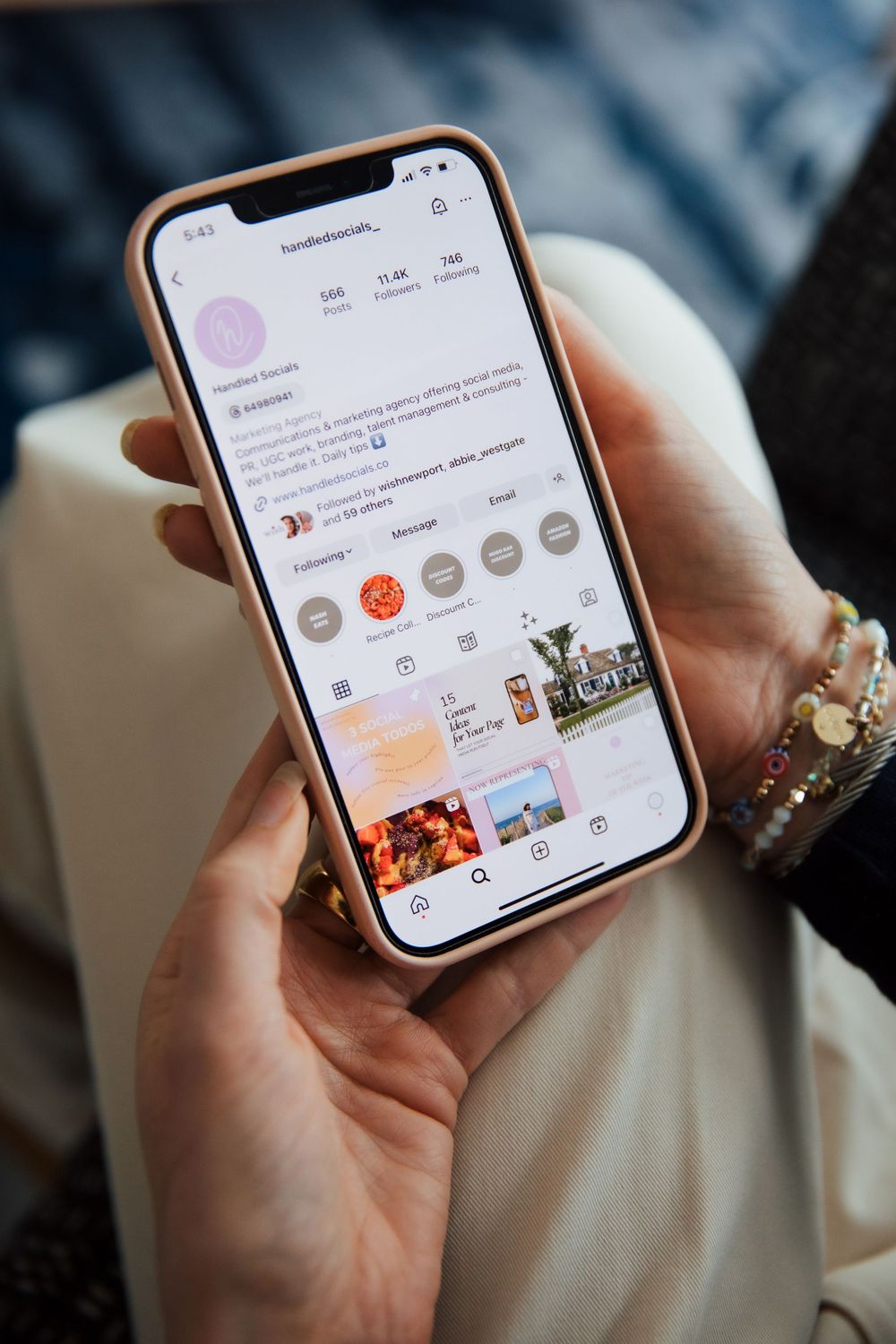 Hand holding iPhone displaying social media profile with story highlights and posts. Branding photography. Newport  RI