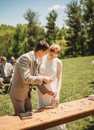 Couple playing a wooden peg game during an outdoor wedding reception on a sunny day.