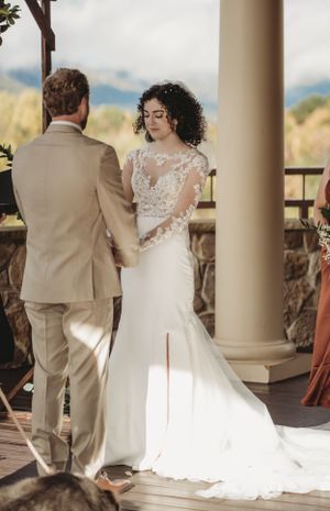 Wedding ceremony under covered porch with bride in lace gown and groomsmen in beige suits.