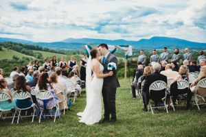 Wedding ceremony overlooking mountain ranges with guests seated in white chairs.