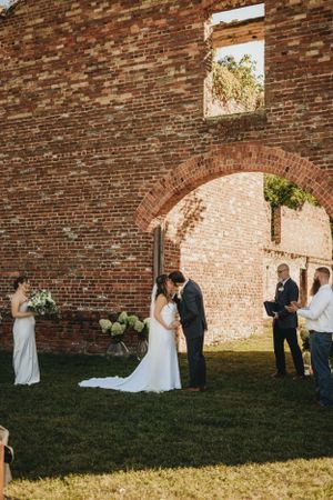 Wedding ceremony in progress against historic brick wall ruins.