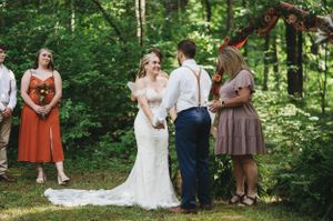 Wedding party gathered in a wooded setting with natural greenery.