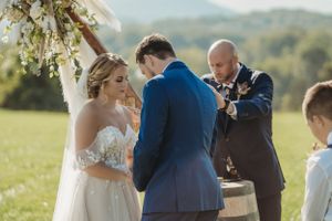 Scenic outdoor wedding ceremony with mountain views and rustic barrel decorations.